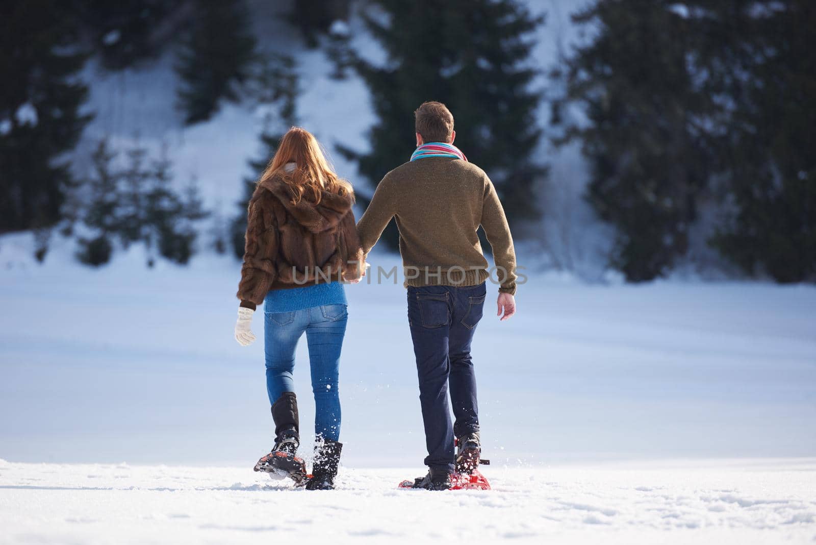 happy young  couple having fun and walking in snow shoes. Romantic winter relaxation scene