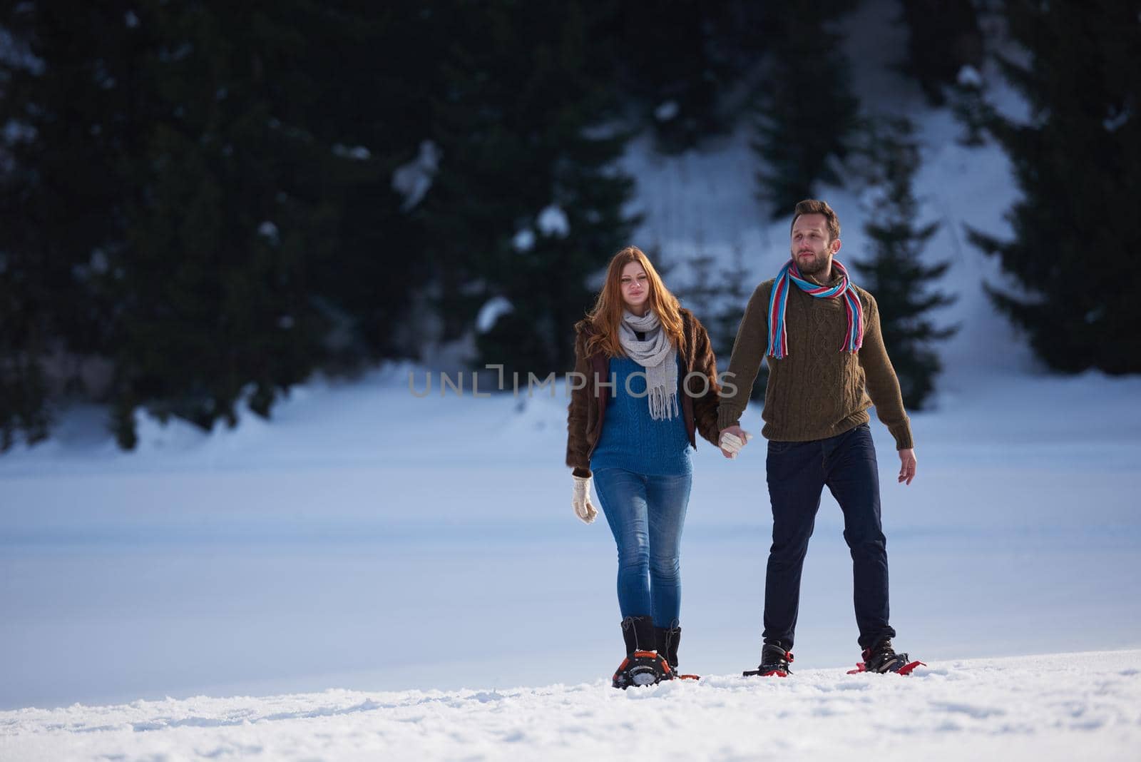 happy young  couple having fun and walking in snow shoes. Romantic winter relaxation scene