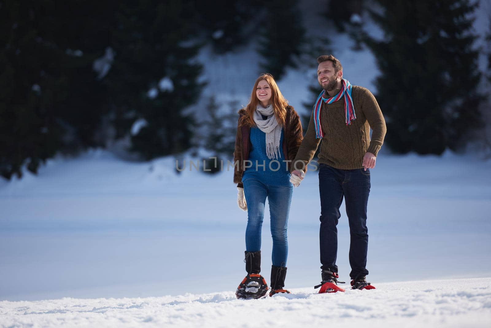 happy young  couple having fun and walking in snow shoes. Romantic winter relaxation scene