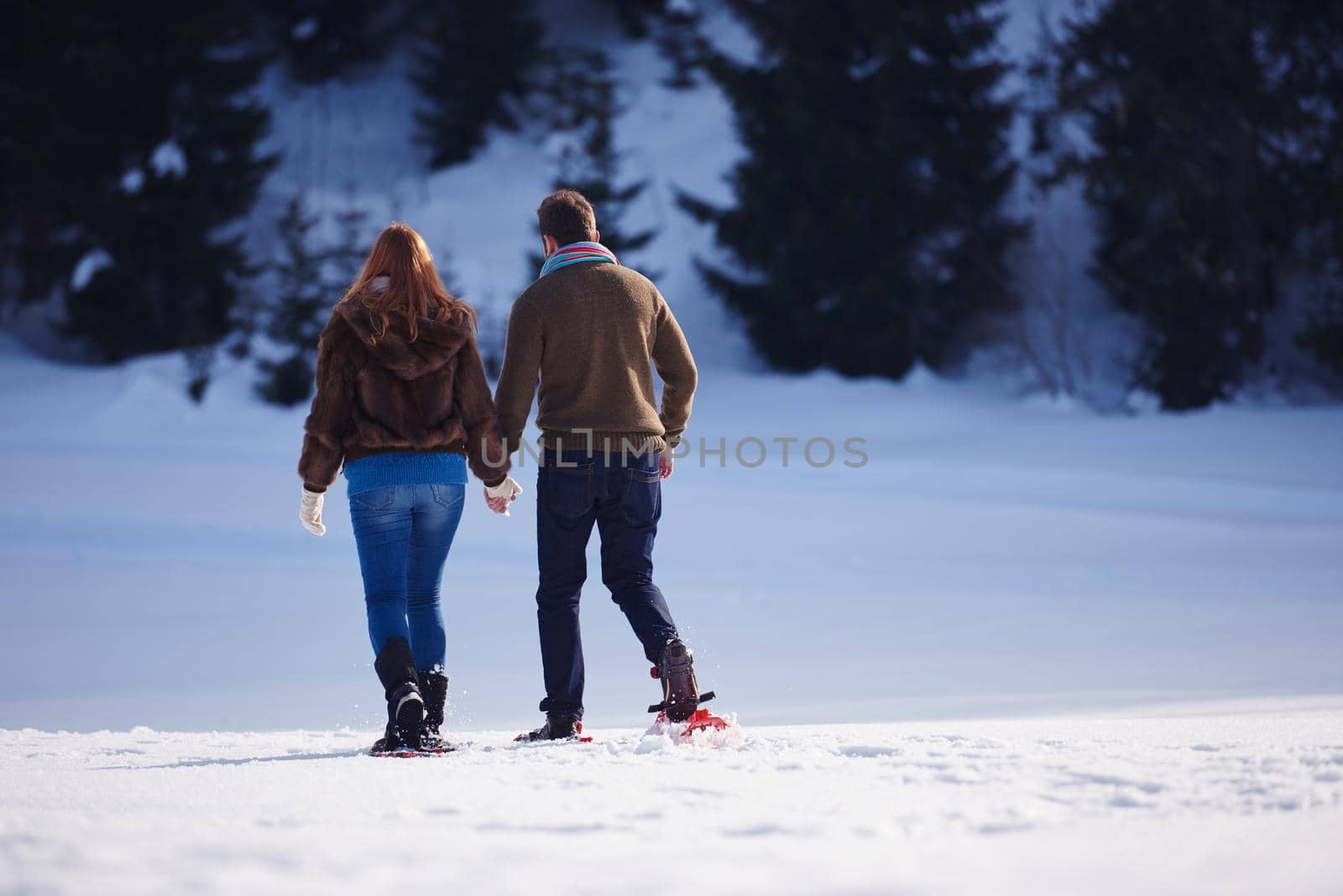 happy young  couple having fun and walking in snow shoes. Romantic winter relaxation scene