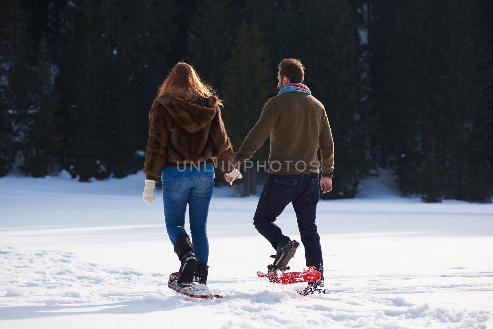 happy young  couple having fun and walking in snow shoes. Romantic winter relaxation scene