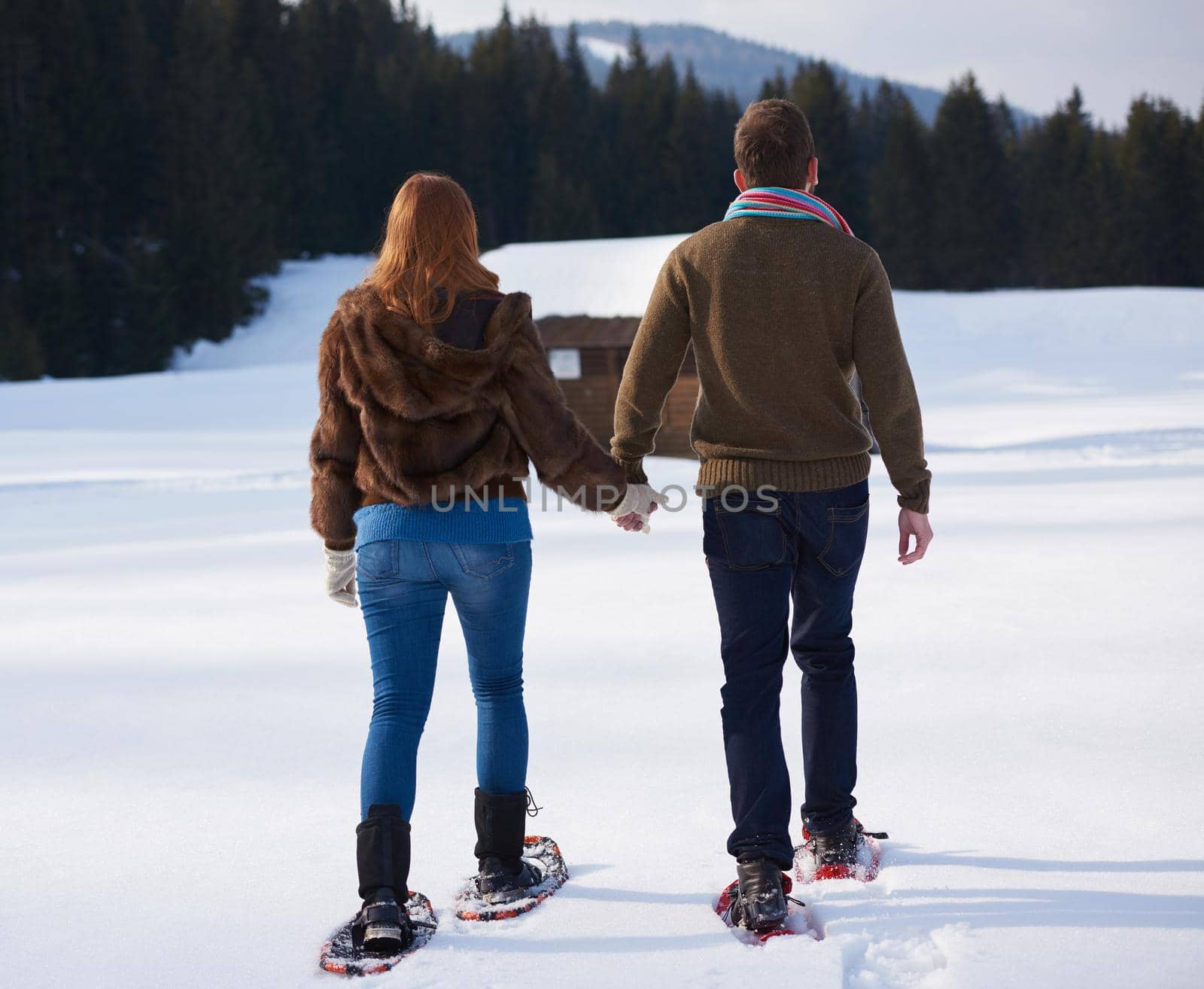 happy young  couple having fun and walking in snow shoes. Romantic winter relaxation scene