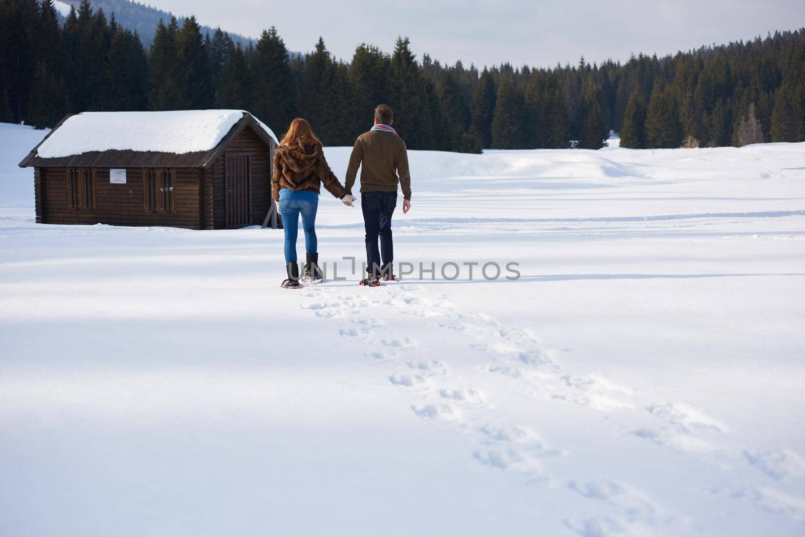 happy young  couple having fun and walking in snow shoes. Romantic winter relaxation scene