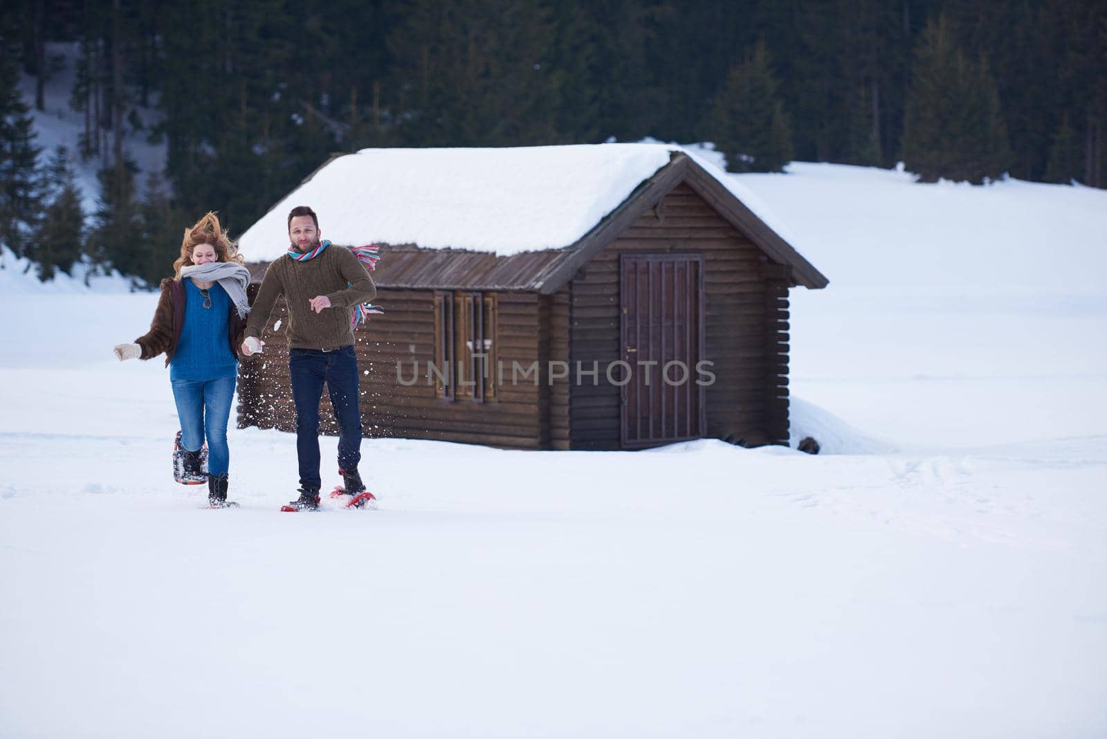 happy young  couple having fun and walking in snow shoes. Romantic winter relaxation scene