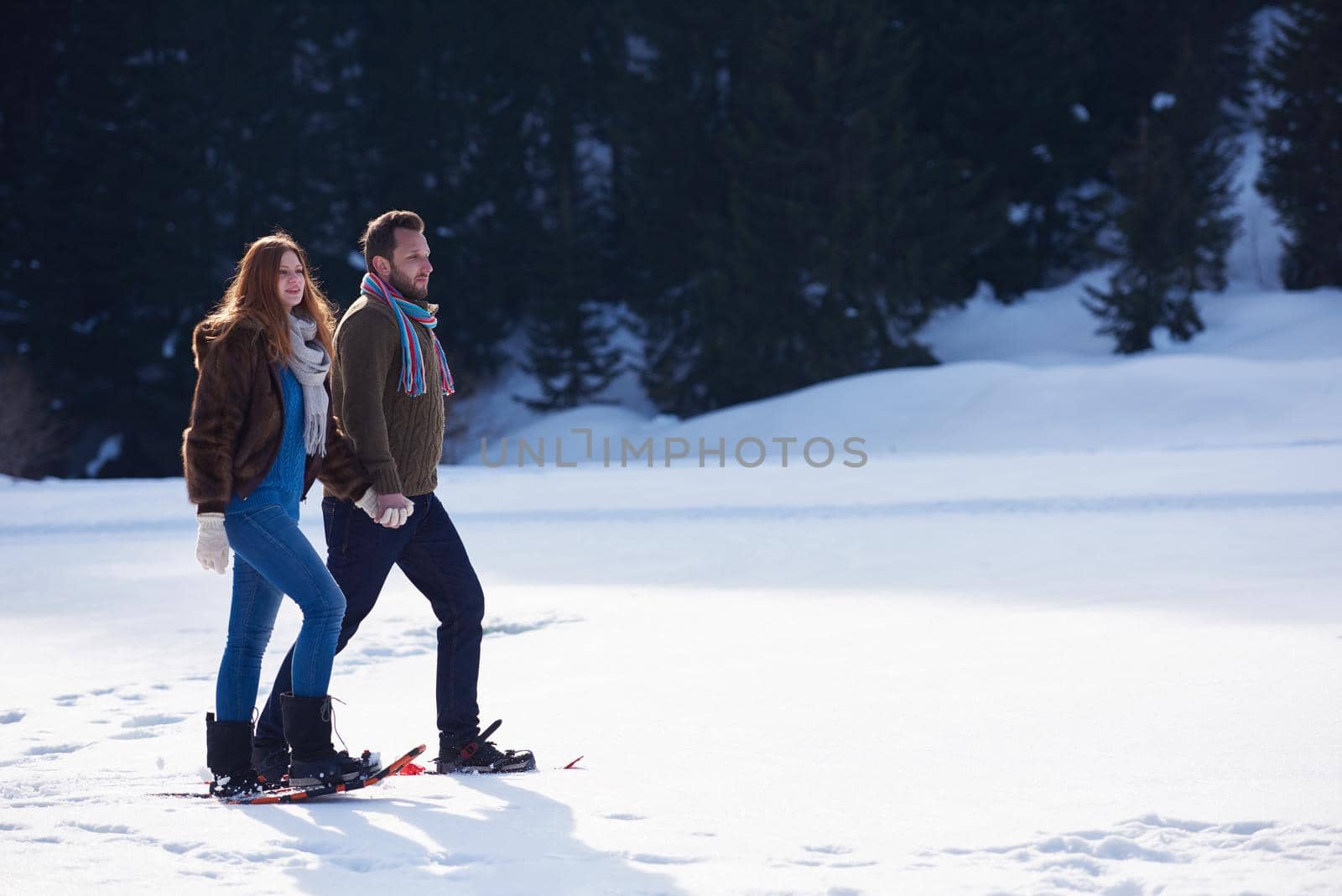 couple having fun and walking in snow shoes by dotshock