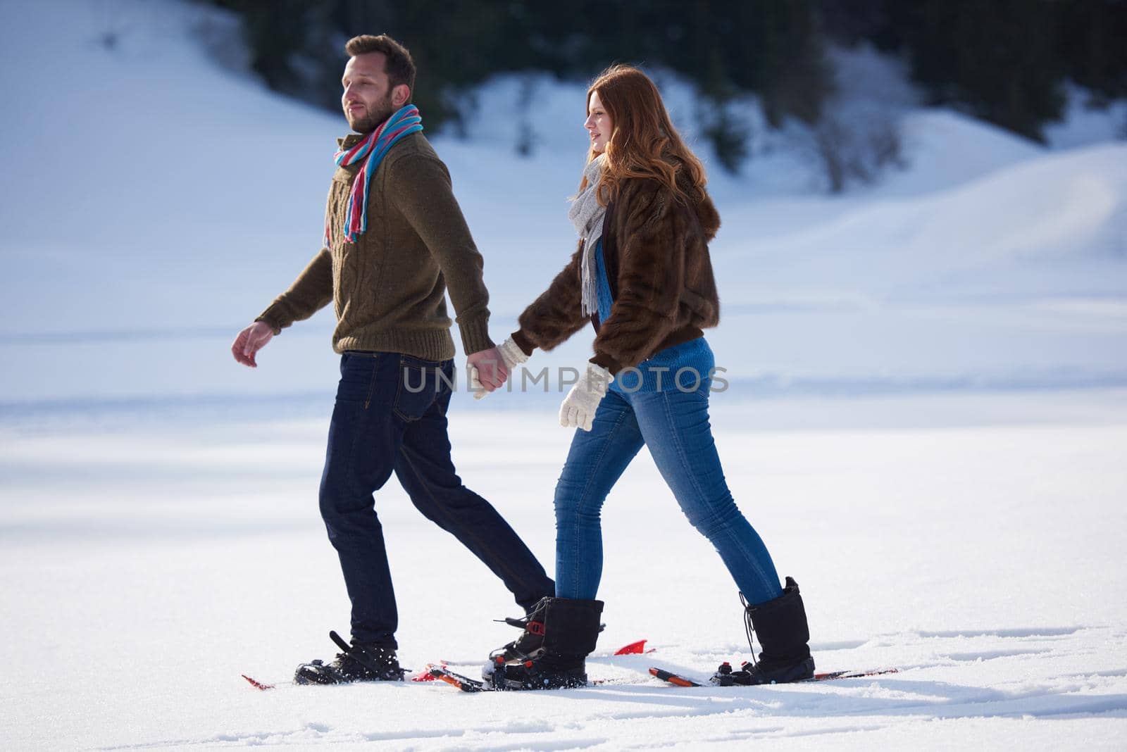 happy young  couple having fun and walking in snow shoes. Romantic winter relaxation scene