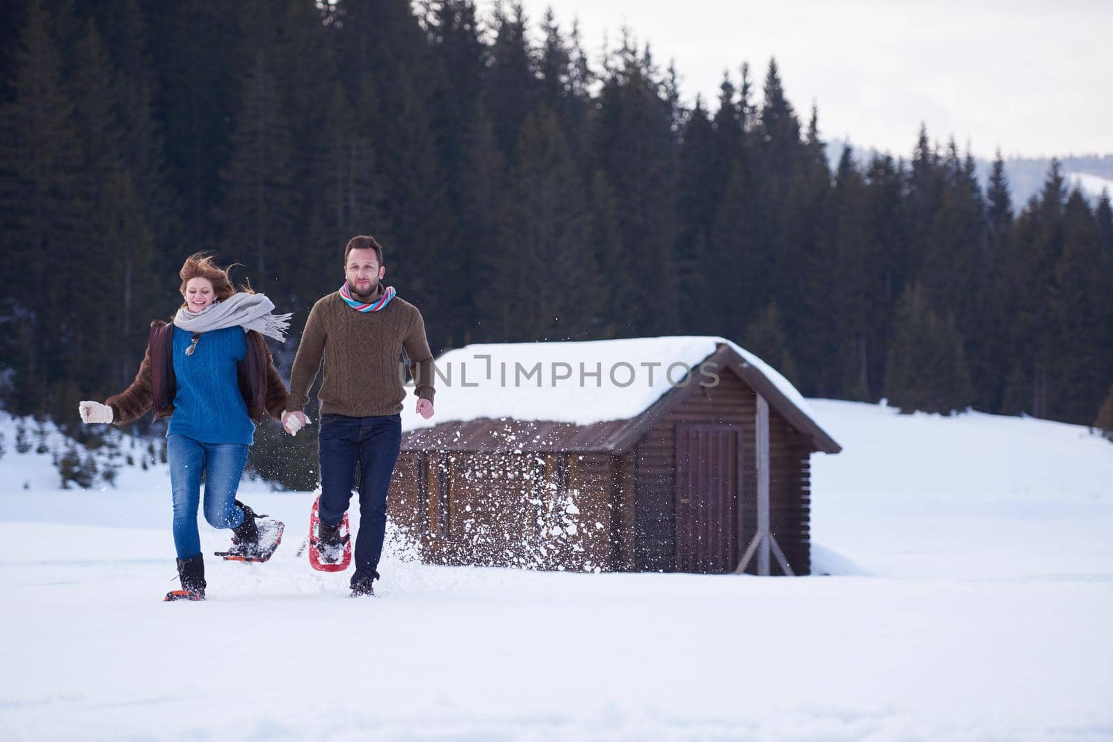 couple having fun and walking in snow shoes by dotshock