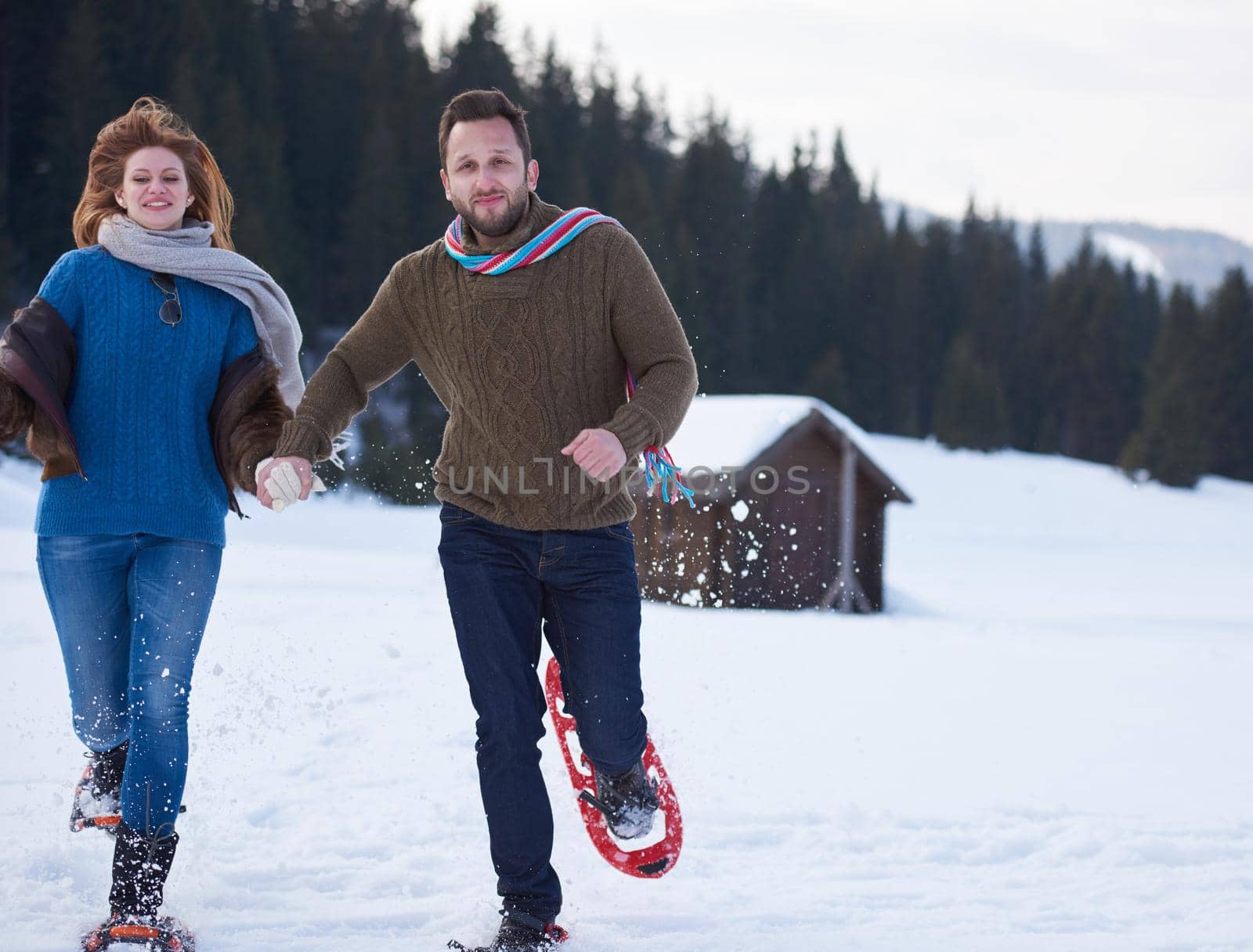 happy young  couple having fun and walking in snow shoes. Romantic winter relaxation scene