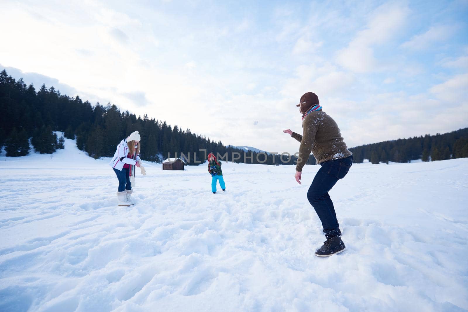 happy young  family playing in fresh snow  at beautiful sunny winter day outdoor in nature