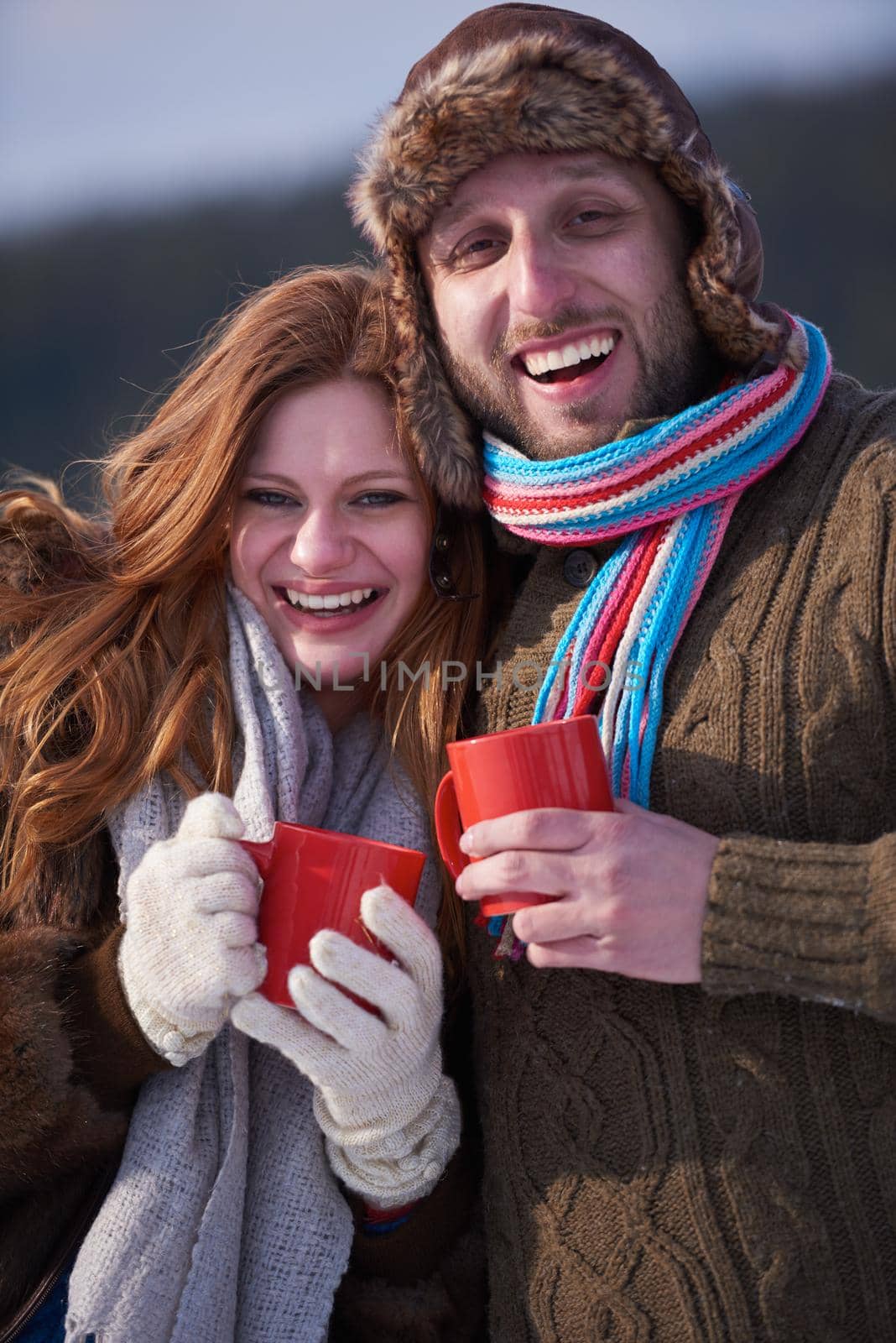 portrait of happy young couple outdoor on winter day drinking warm tea