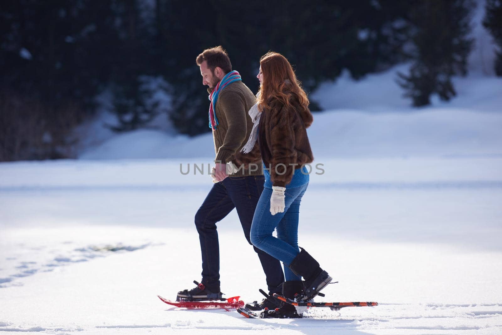 happy young  couple having fun and walking in snow shoes. Romantic winter relaxation scene