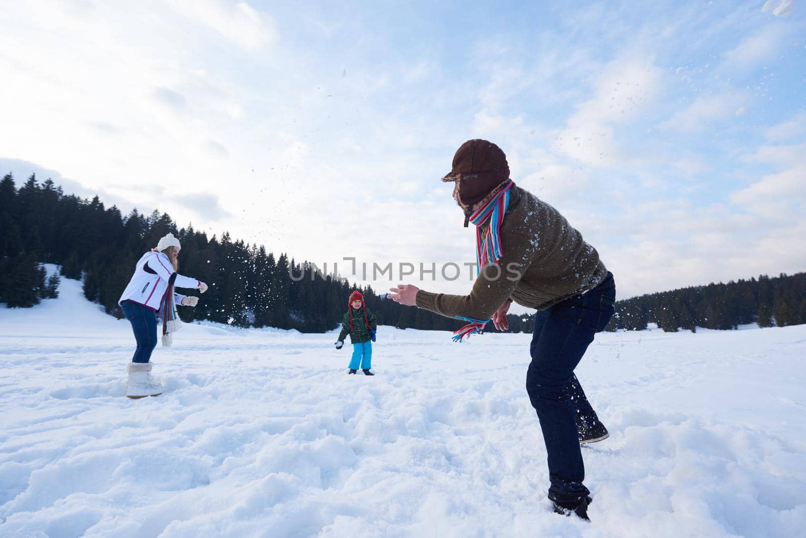 happy young  family playing in fresh snow  at beautiful sunny winter day outdoor in nature