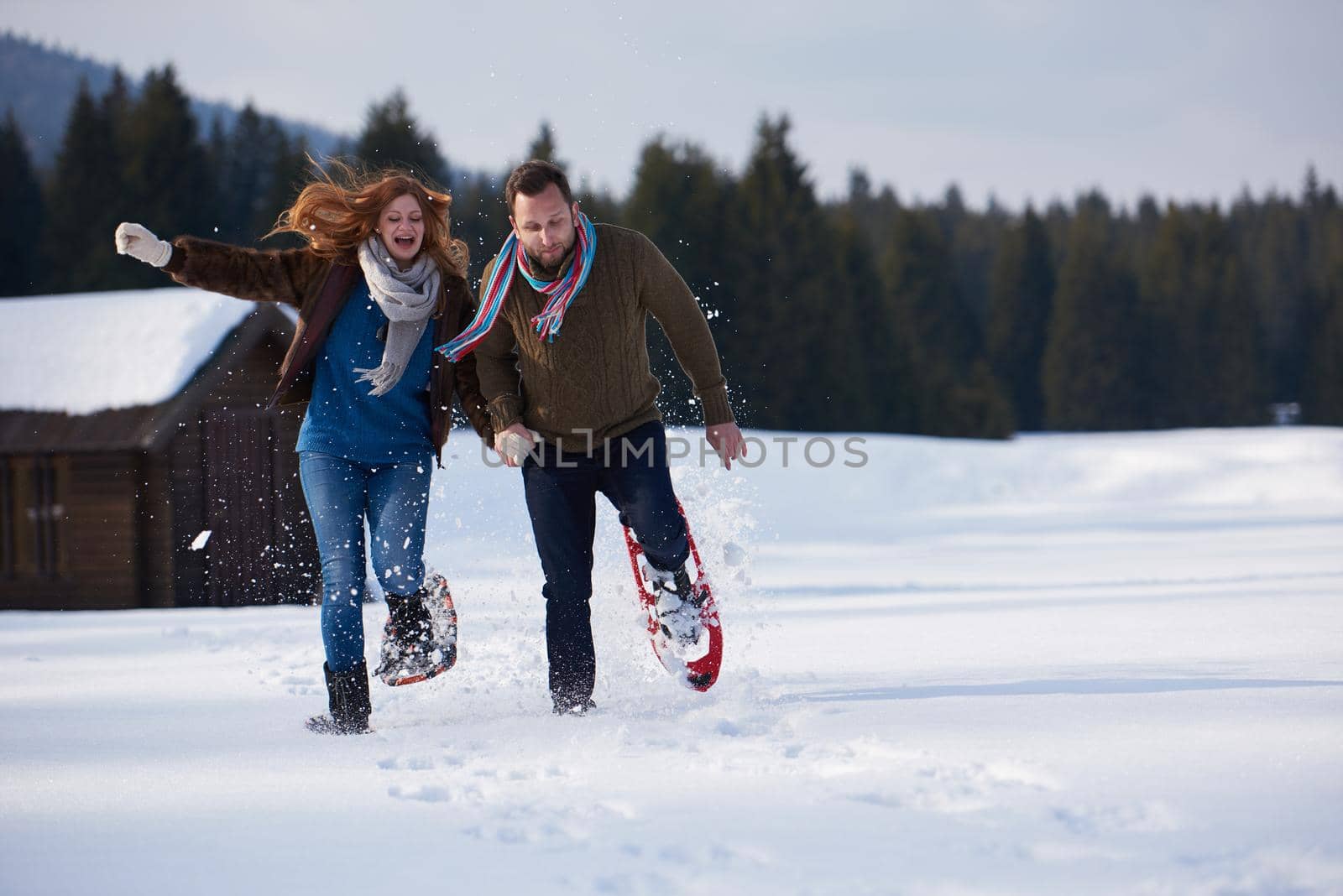 happy young  couple having fun and walking in snow shoes. Romantic winter relaxation scene