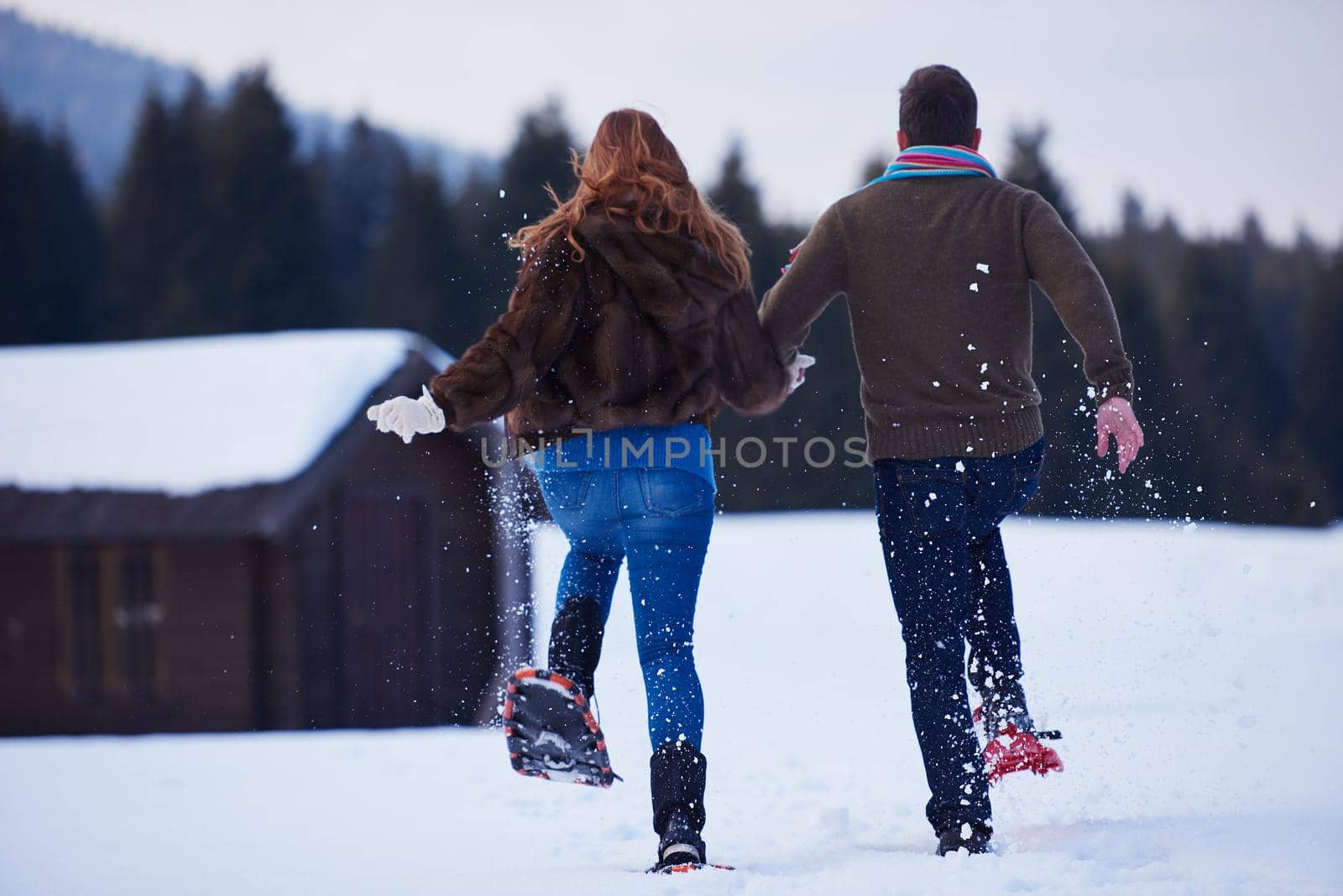 happy young  couple having fun and walking in snow shoes. Romantic winter relaxation scene