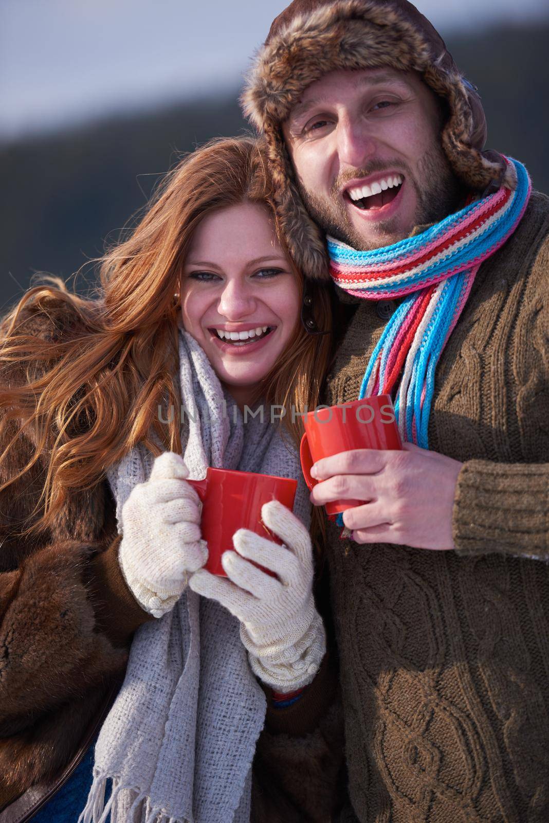 portrait of happy young couple outdoor on winter day drinking warm tea