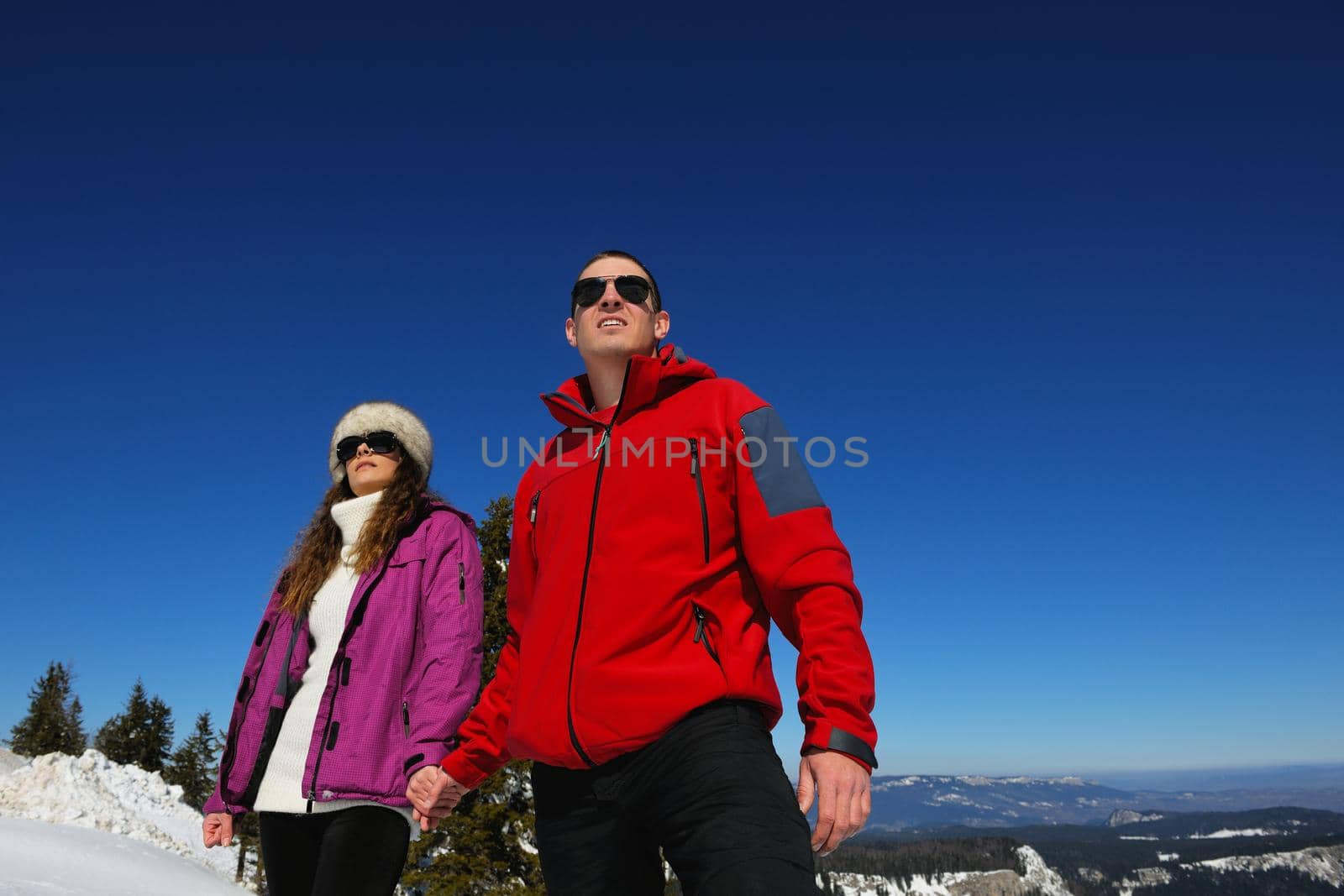 Happy young couple has fun on fresh snow at beautiful winter sunny day on relaxing vacation