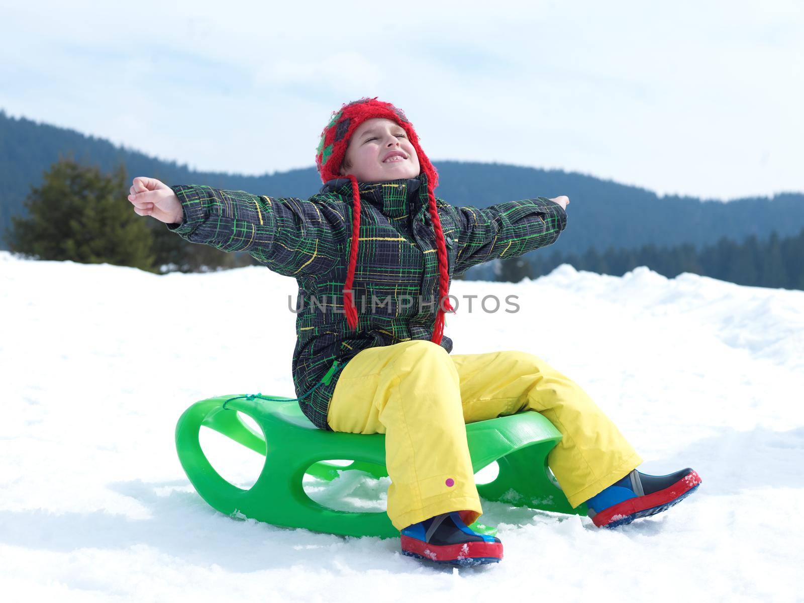 happy young boy have fun on winter vacatioin, sledding children on fresh snow at sunny day outdoor in nature