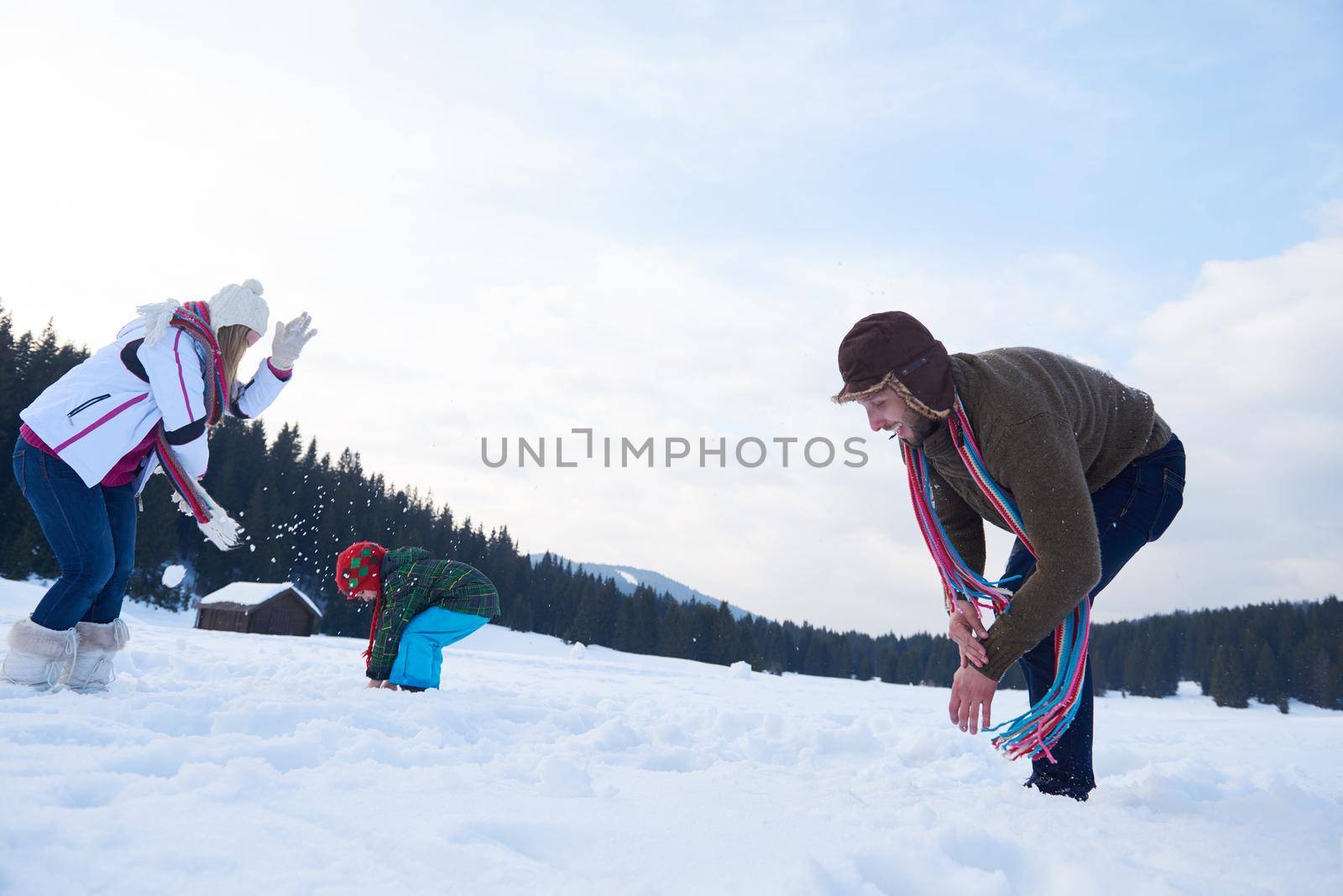 happy young  family playing in fresh snow  at beautiful sunny winter day outdoor in nature