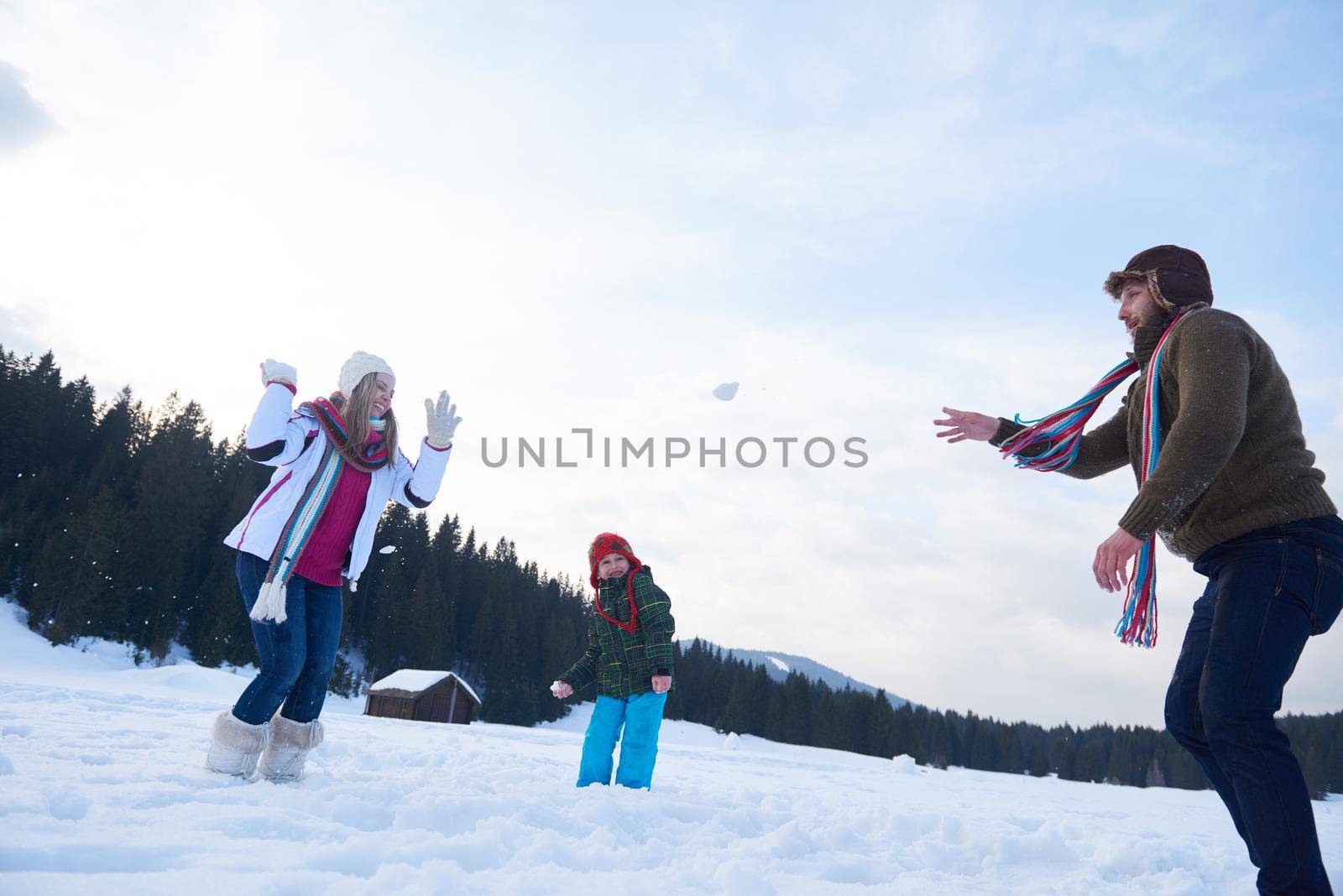 happy young  family playing in fresh snow  at beautiful sunny winter day outdoor in nature