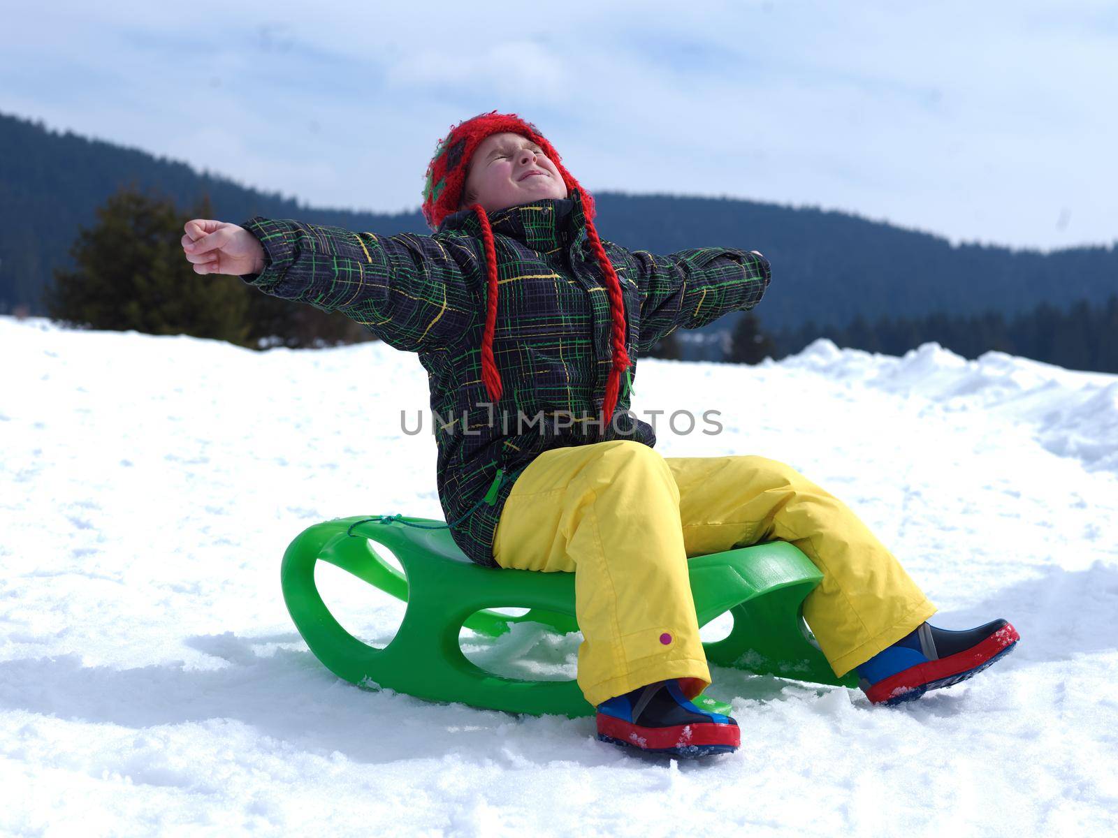 happy young boy have fun on winter vacatioin, sledding children on fresh snow at sunny day outdoor in nature