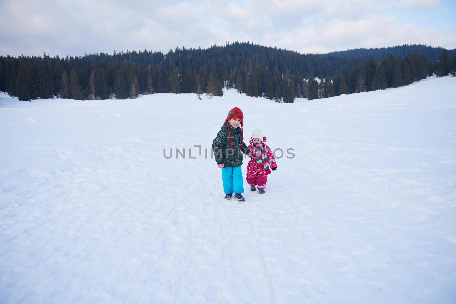 kids walking on snow at winter vacation in forest. happy children group have fun outdoor