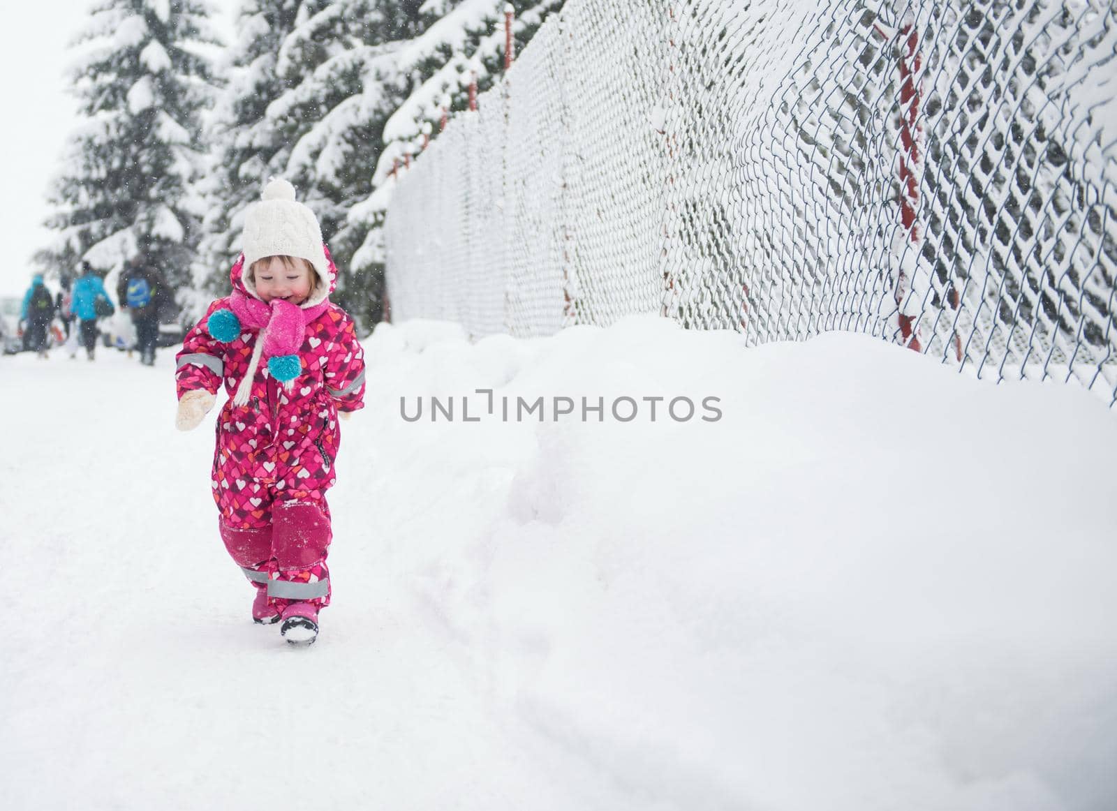 portrait of happy smiling little girl outdoors, having fun and playing on fresh snow on snowy  winter day