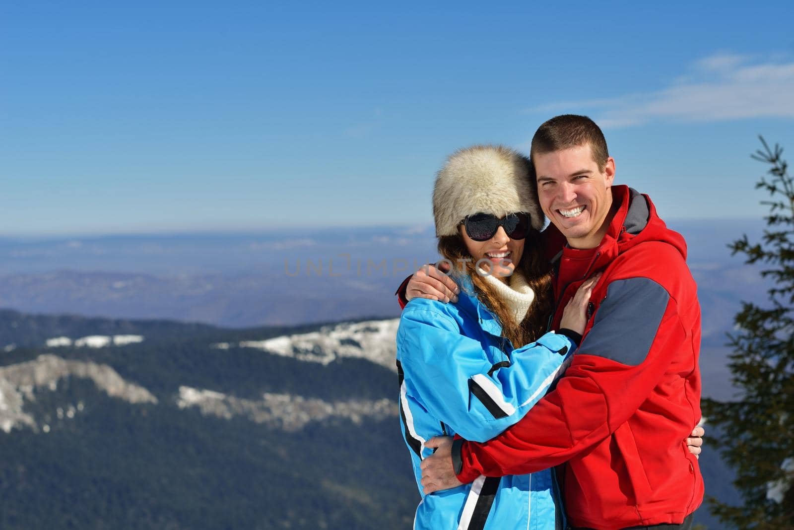 Happy young couple has fun on fresh snow at beautiful winter sunny day on vacation