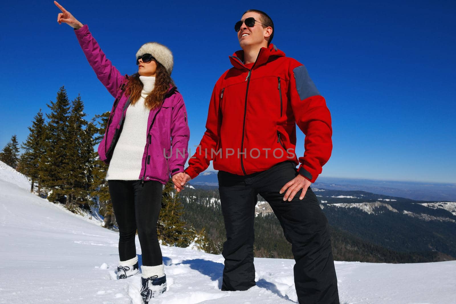 Happy young couple has fun on fresh snow at beautiful winter sunny day on vacation