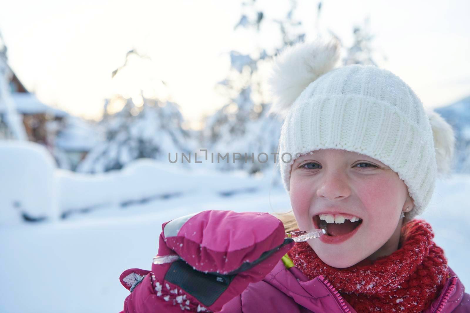 cute little girl  while eating icicle  on beautiful winter day by dotshock