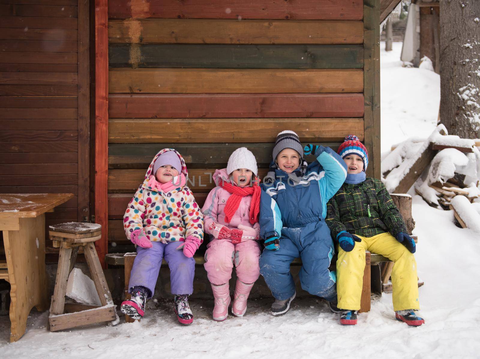 little children group sitting  together  in front of wooden cabin by dotshock