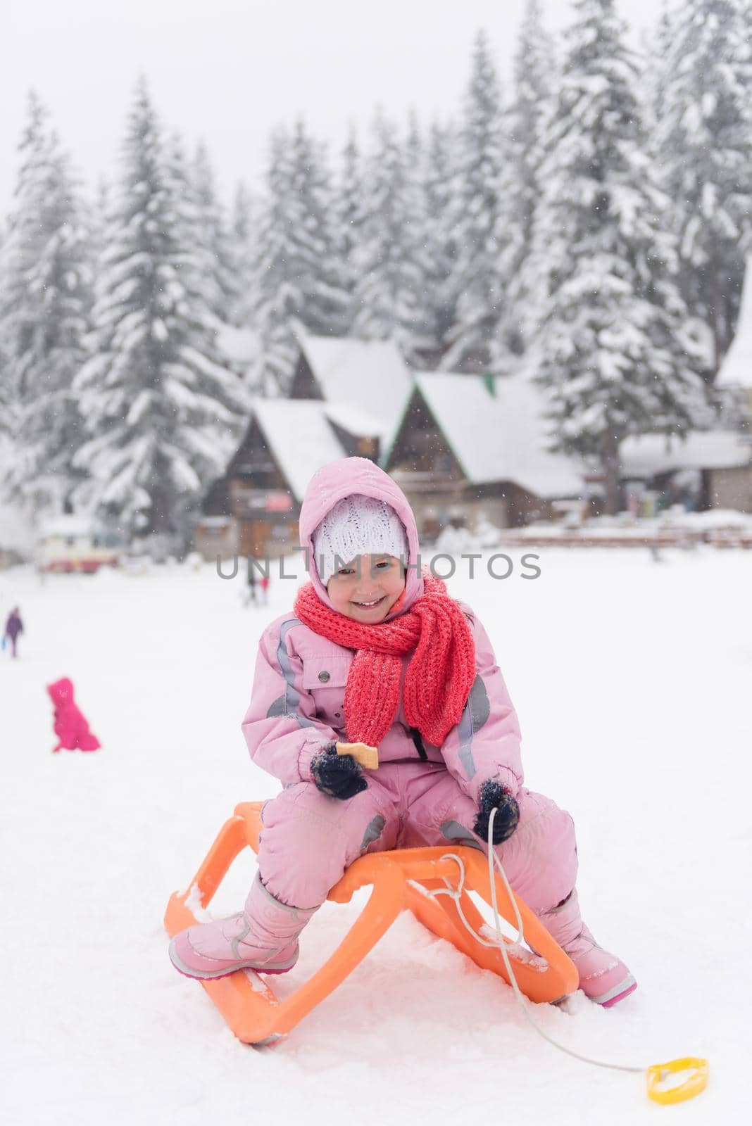 portrait of cute little girl child sitting on sledges at winter day with fresh snow,  eat cookies and have break