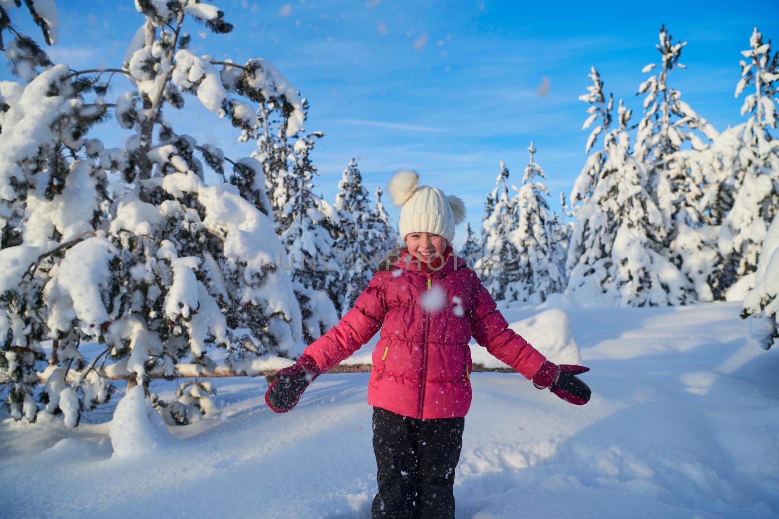 little girl having fun  throwing fresh snow at beautiful sunny winter day