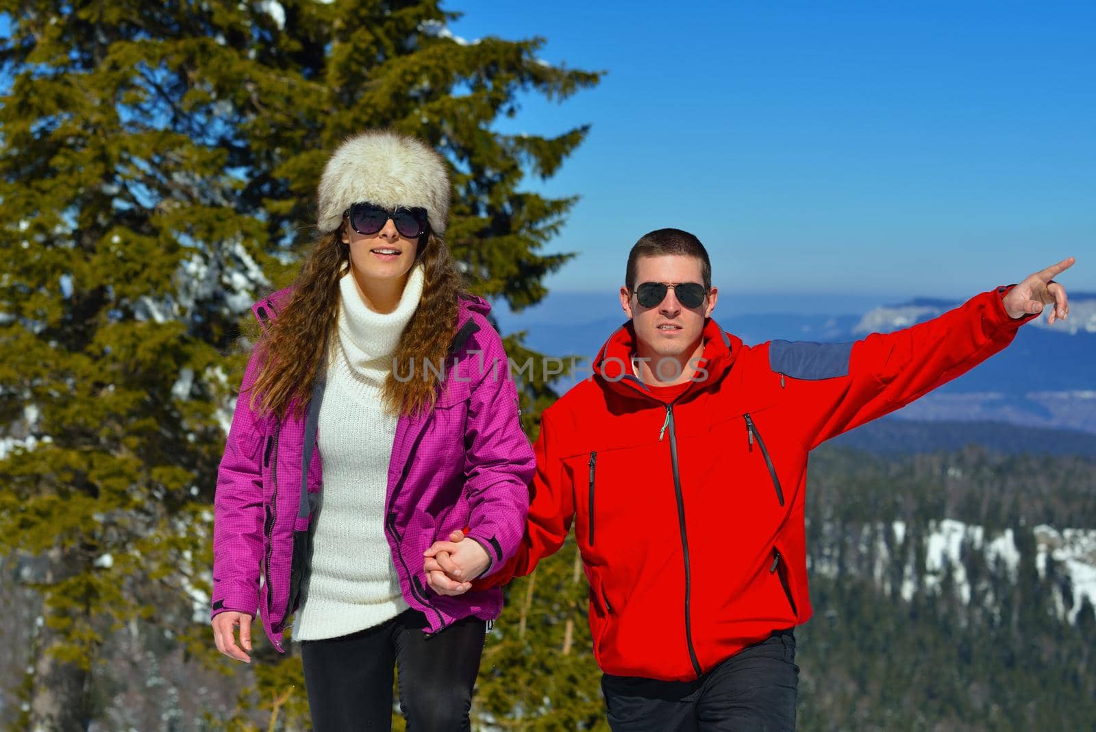 Happy young couple has fun on fresh snow at beautiful winter sunny day on vacation