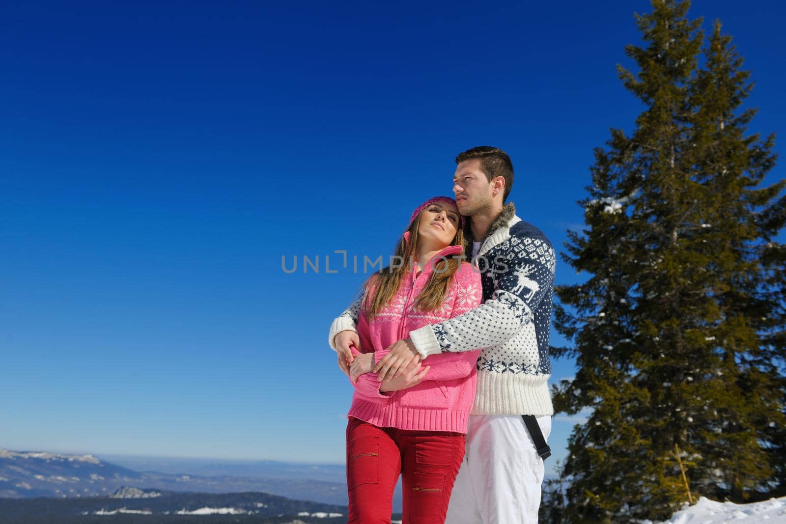 Happy young couple has fun on fresh snow at beautiful winter sunny day on vacation