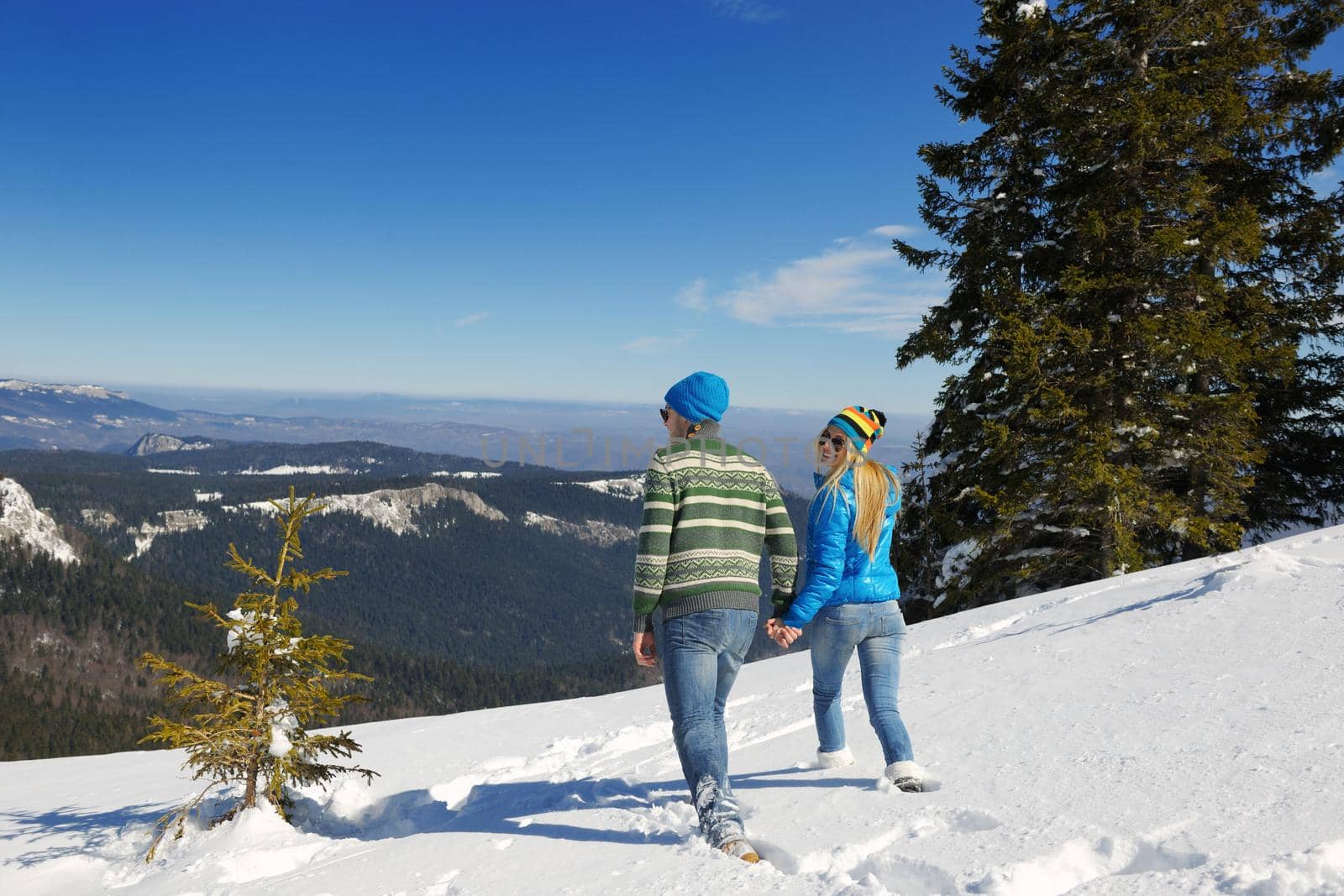 Happy young couple has fun on fresh snow at beautiful winter sunny day on vacation