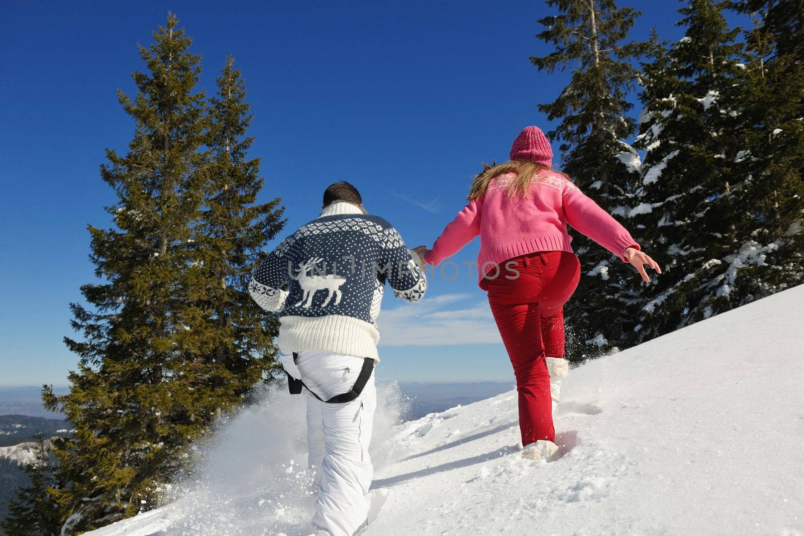 Happy young couple has fun on fresh snow at beautiful winter sunny day on vacation