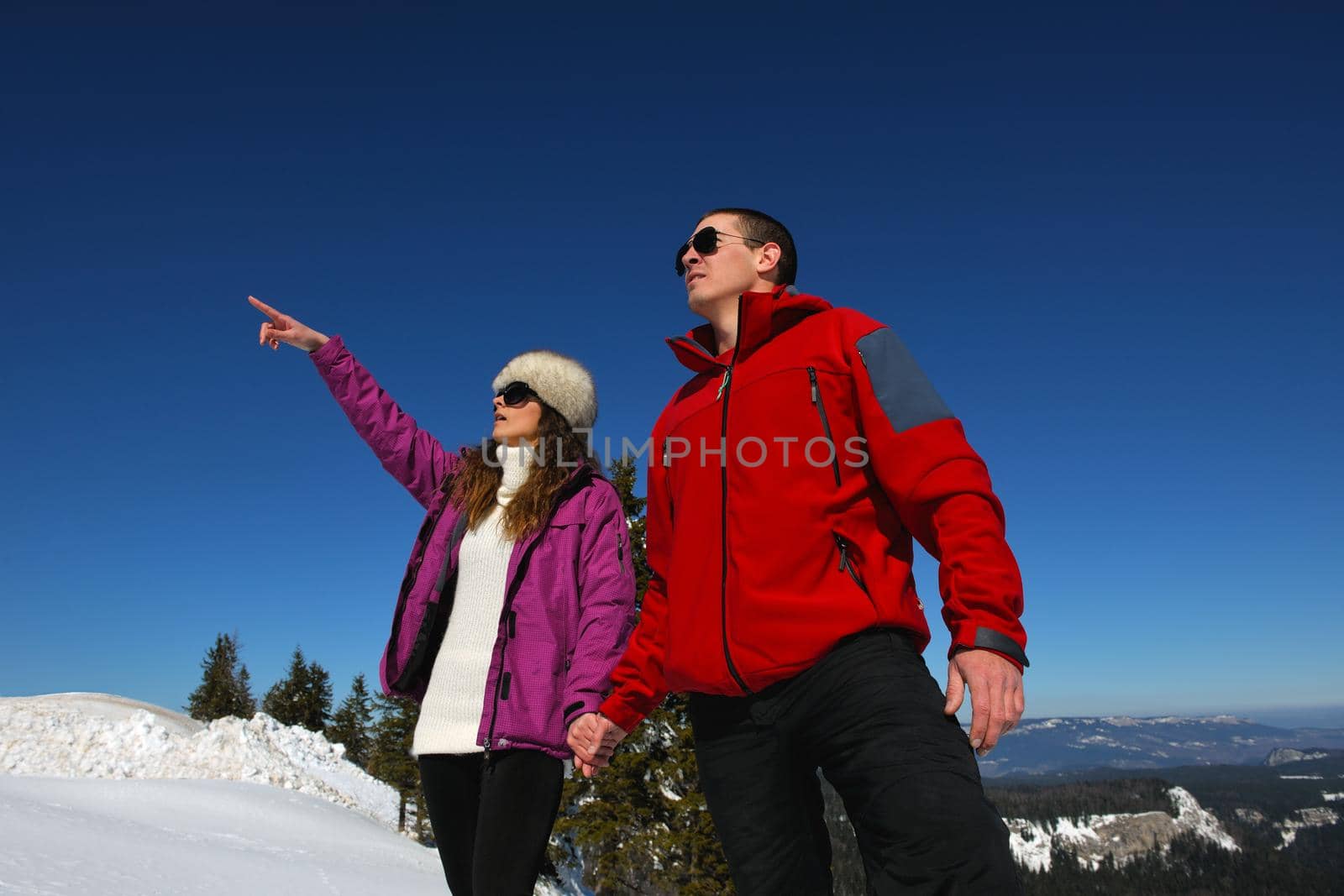 Happy young couple has fun on fresh snow at beautiful winter sunny day on relaxing vacation