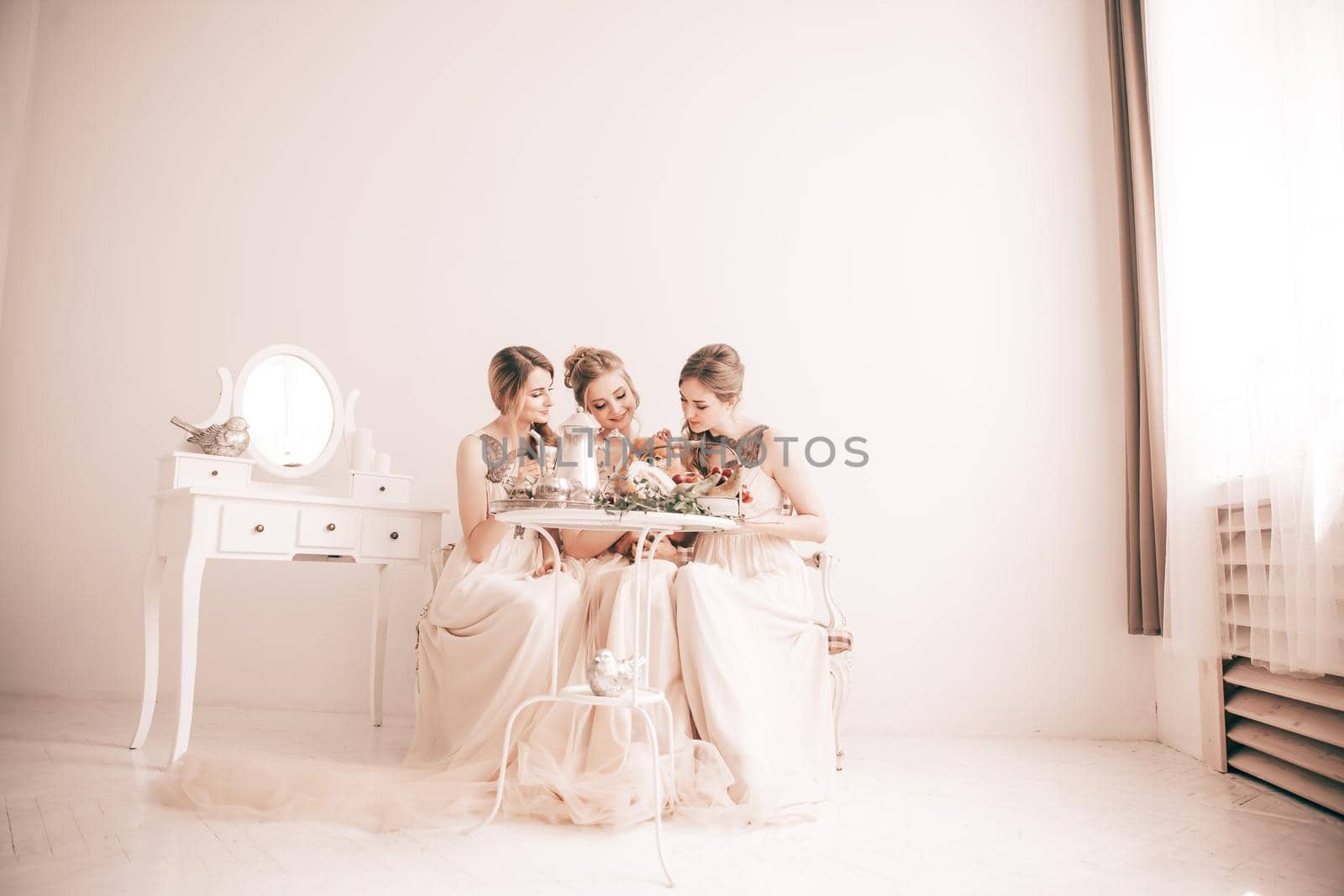 bride and her friends sitting at the festive table in a stylish boudoir.