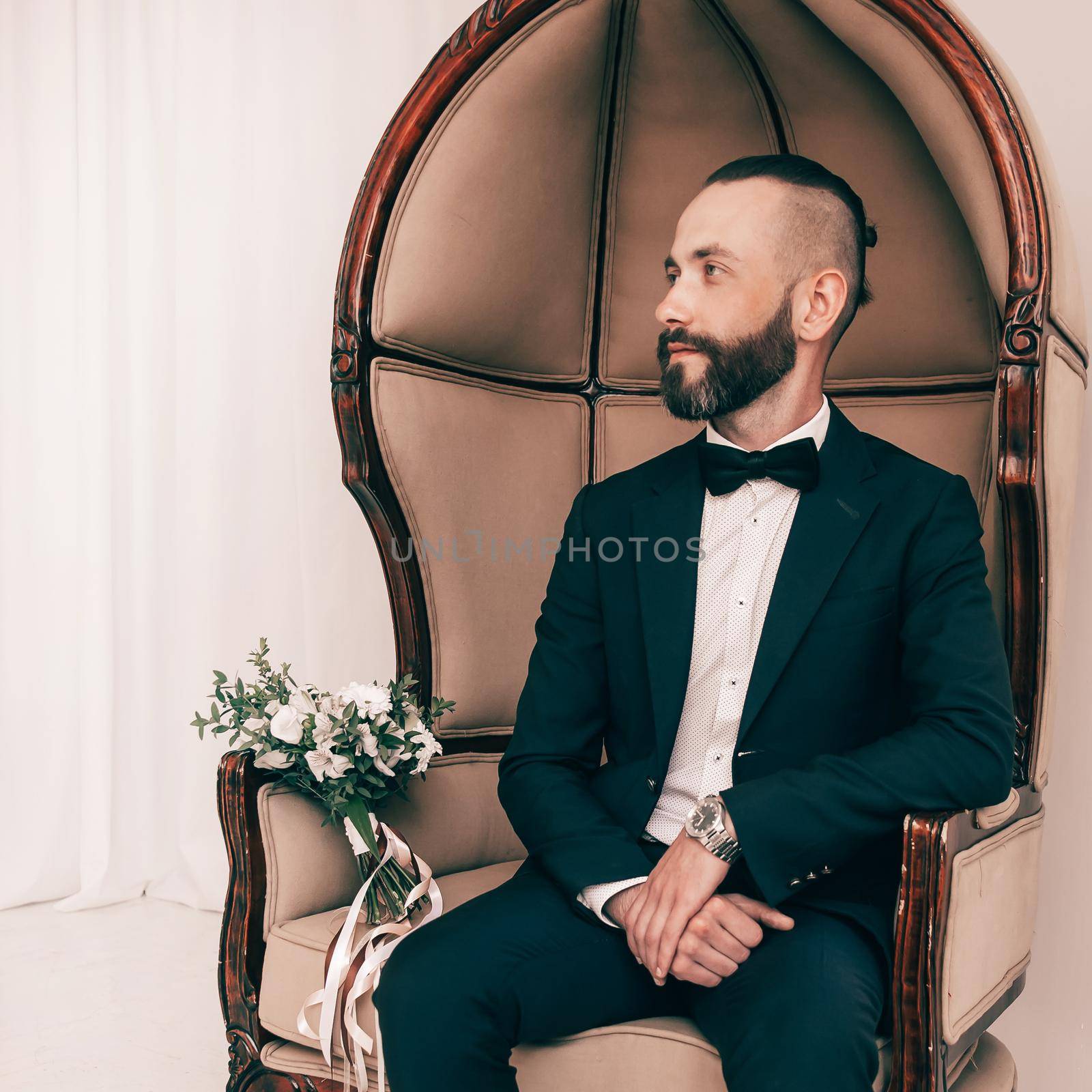 in full growth. elegant man sitting in a chair by SmartPhotoLab