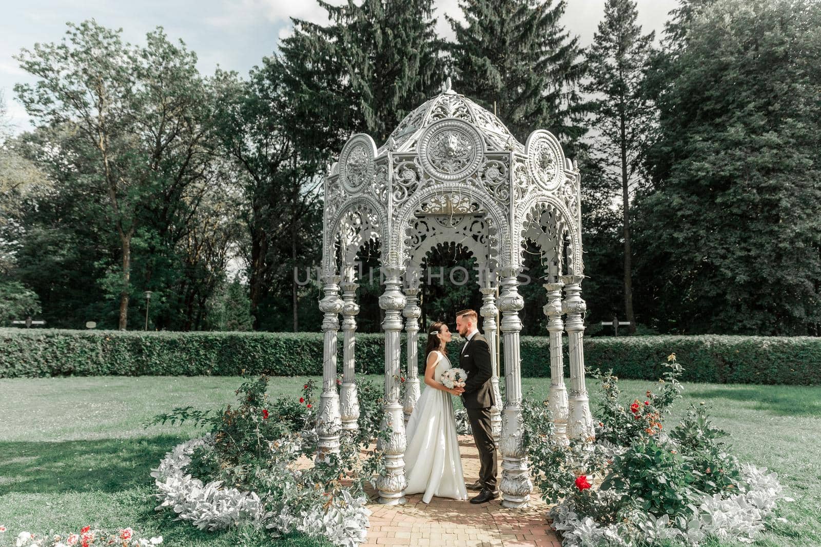 happy bride and groom standing in arched gazebo .holidays and events
