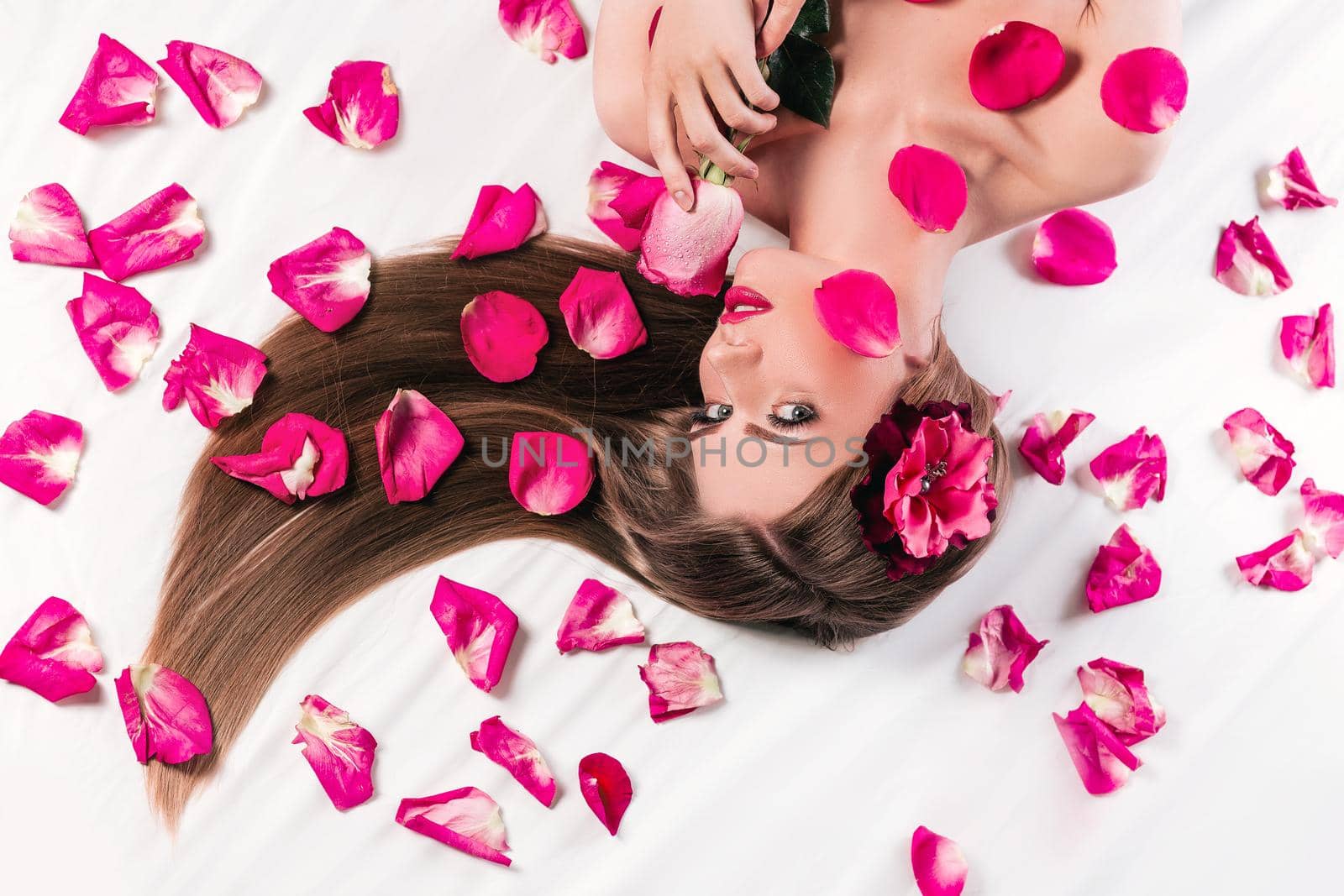 beautiful fashionable girl lying among rose petals. photo with copy space