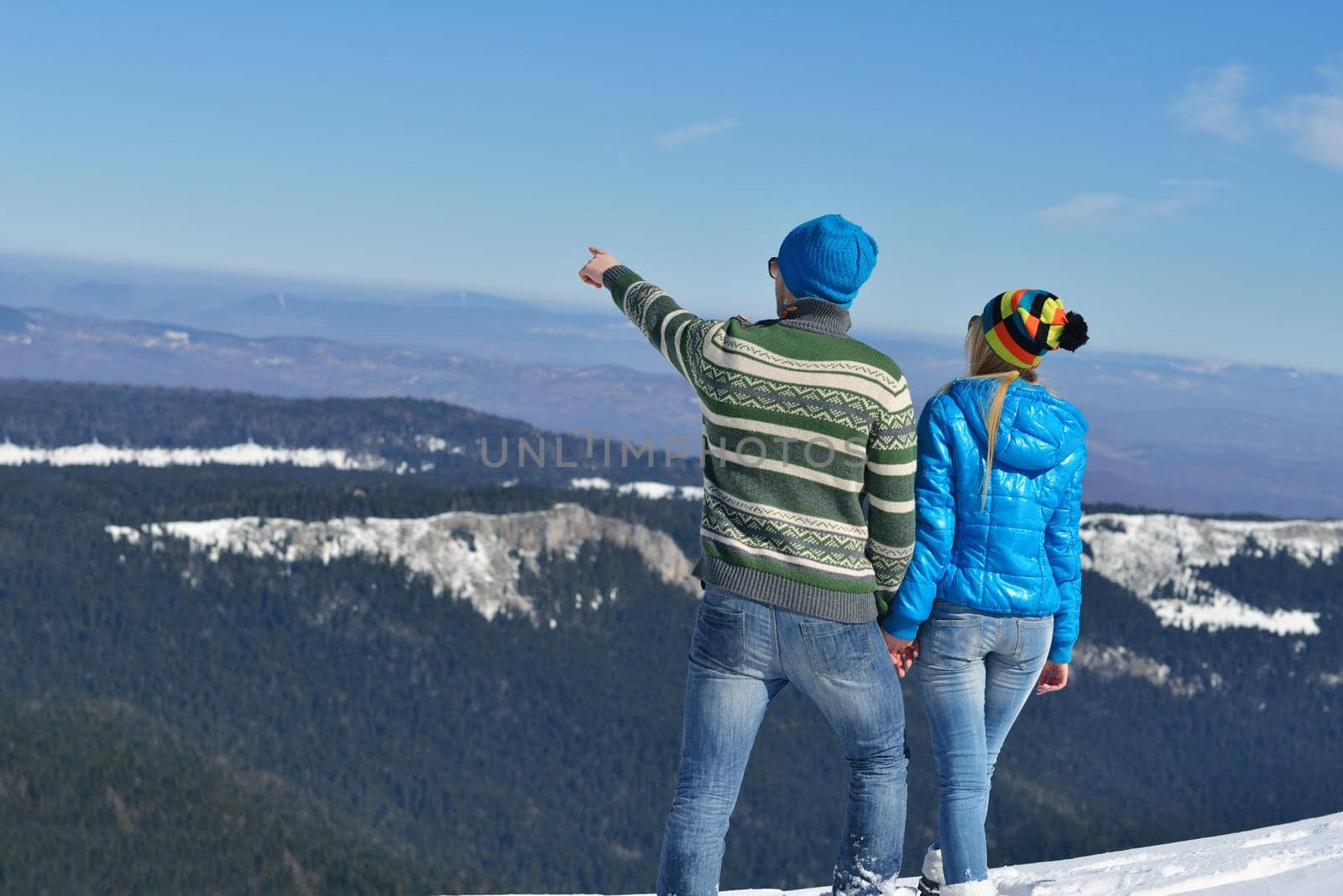 Happy young couple has fun on fresh snow at beautiful winter sunny day on vacation