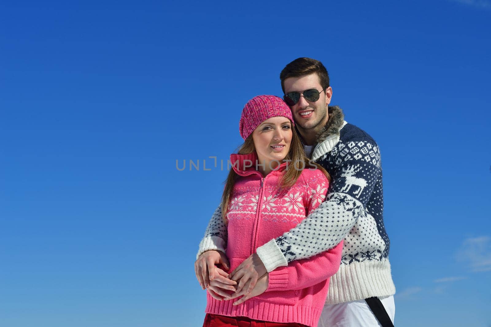 Happy young couple has fun on fresh snow at beautiful winter sunny day on vacation