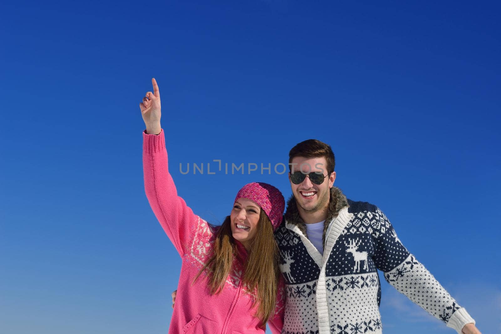 Happy young couple has fun on fresh snow at beautiful winter sunny day on vacation