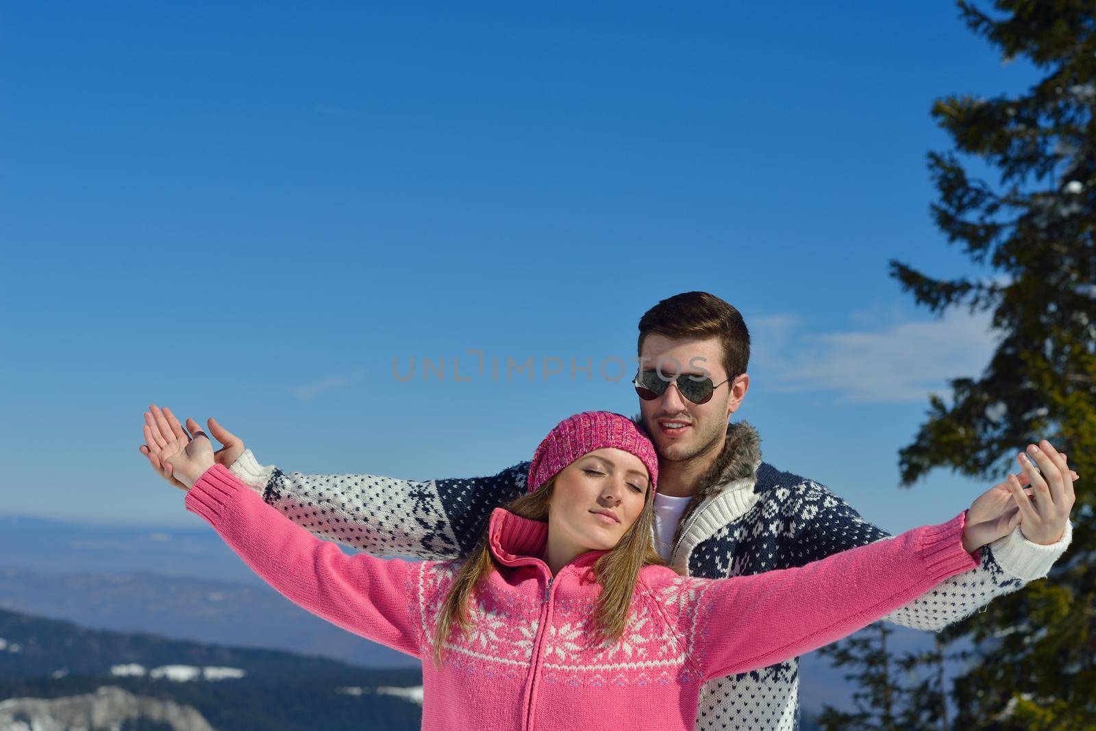 Happy young couple has fun on fresh snow at beautiful winter sunny day on vacation