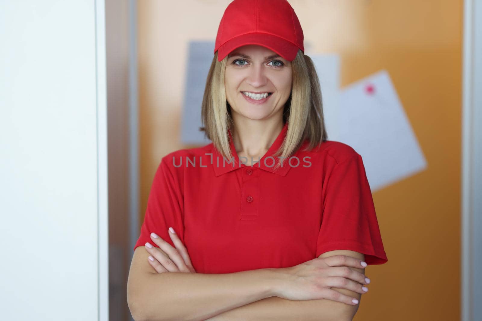 Happy blonde lady courier in red shirt and cap uniform by kuprevich