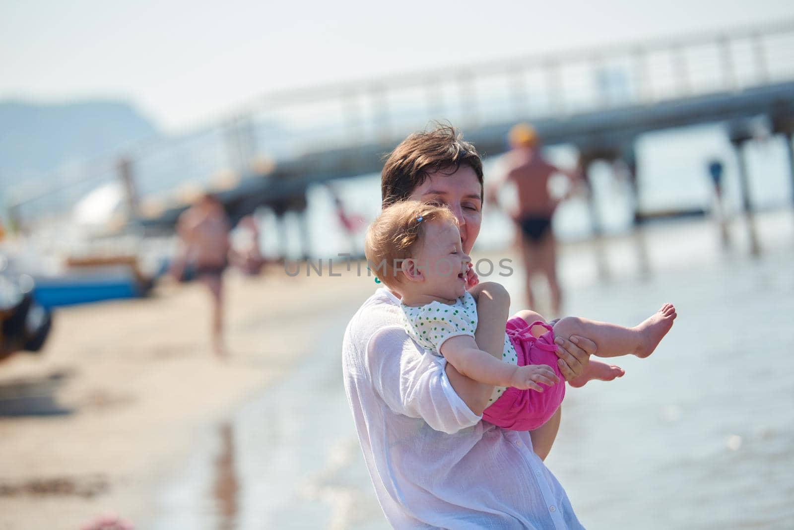 happy mom and baby on beach  have fun while learning to walk and  make first steps