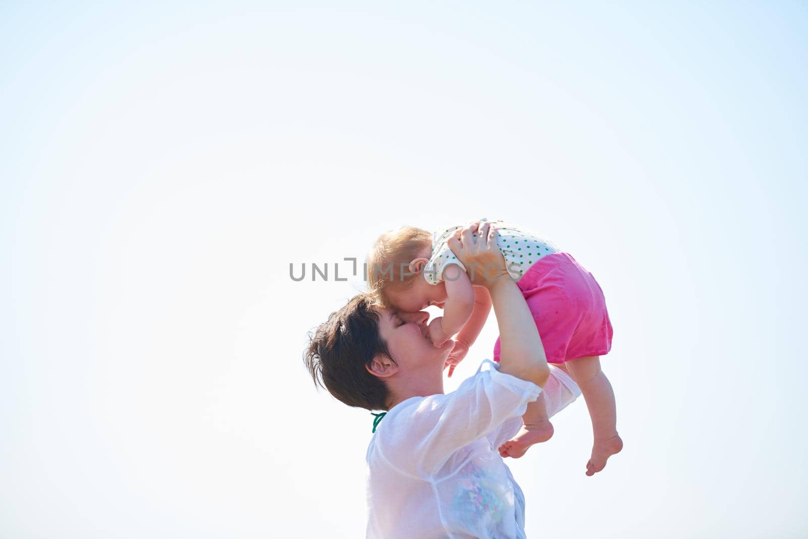 happy mom and baby on beach  have fun while learning to walk and  make first steps