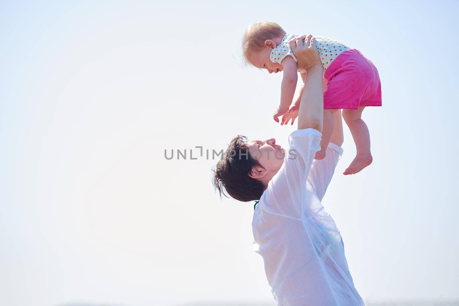 happy mom and baby on beach  have fun while learning to walk and  make first steps