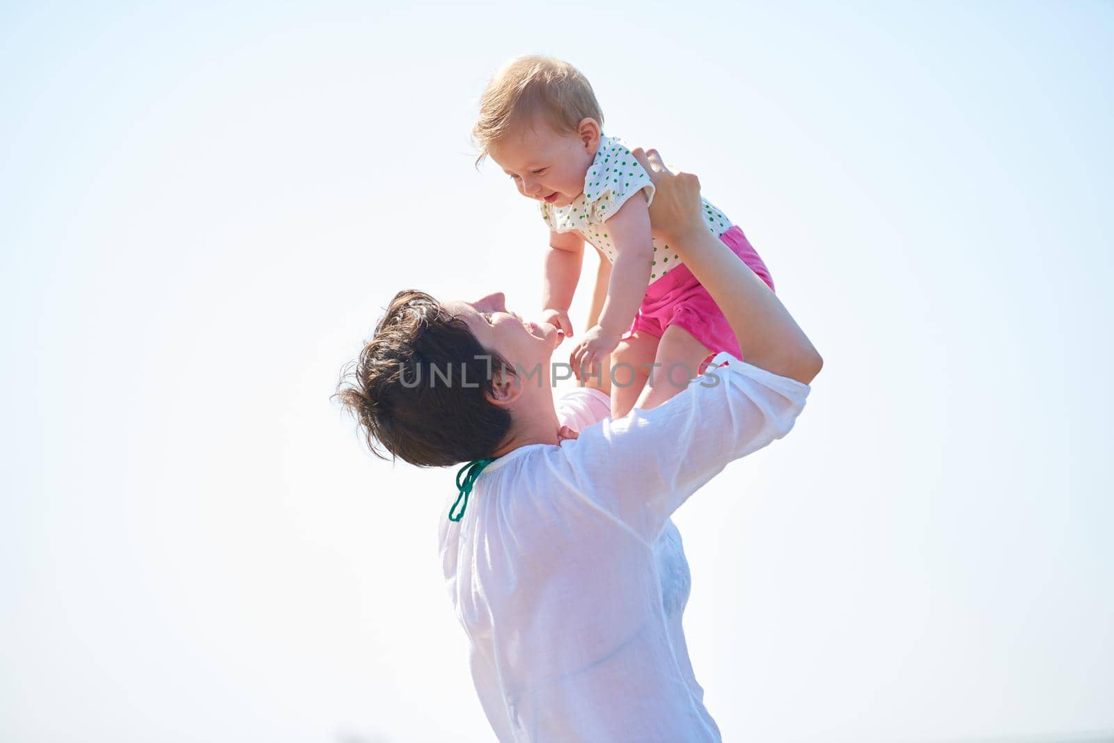 happy mom and baby on beach  have fun while learning to walk and  make first steps